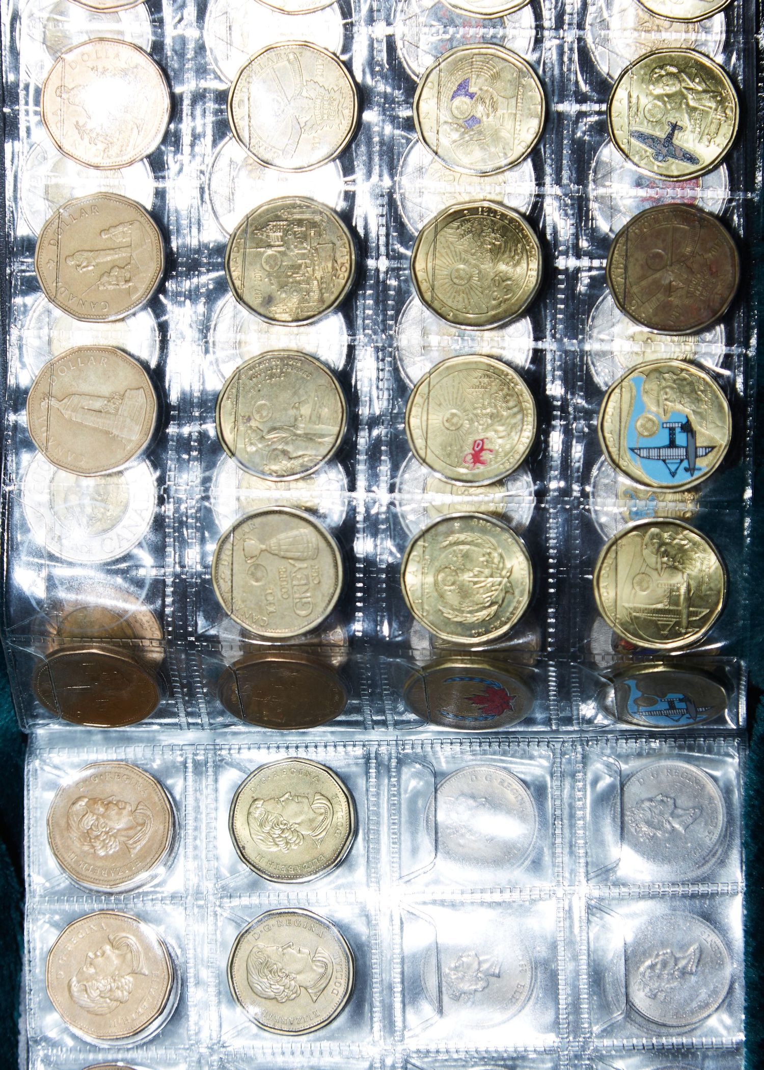 Collection of commemorative coins arranged in plastic sleeves showing various designs and patterns.