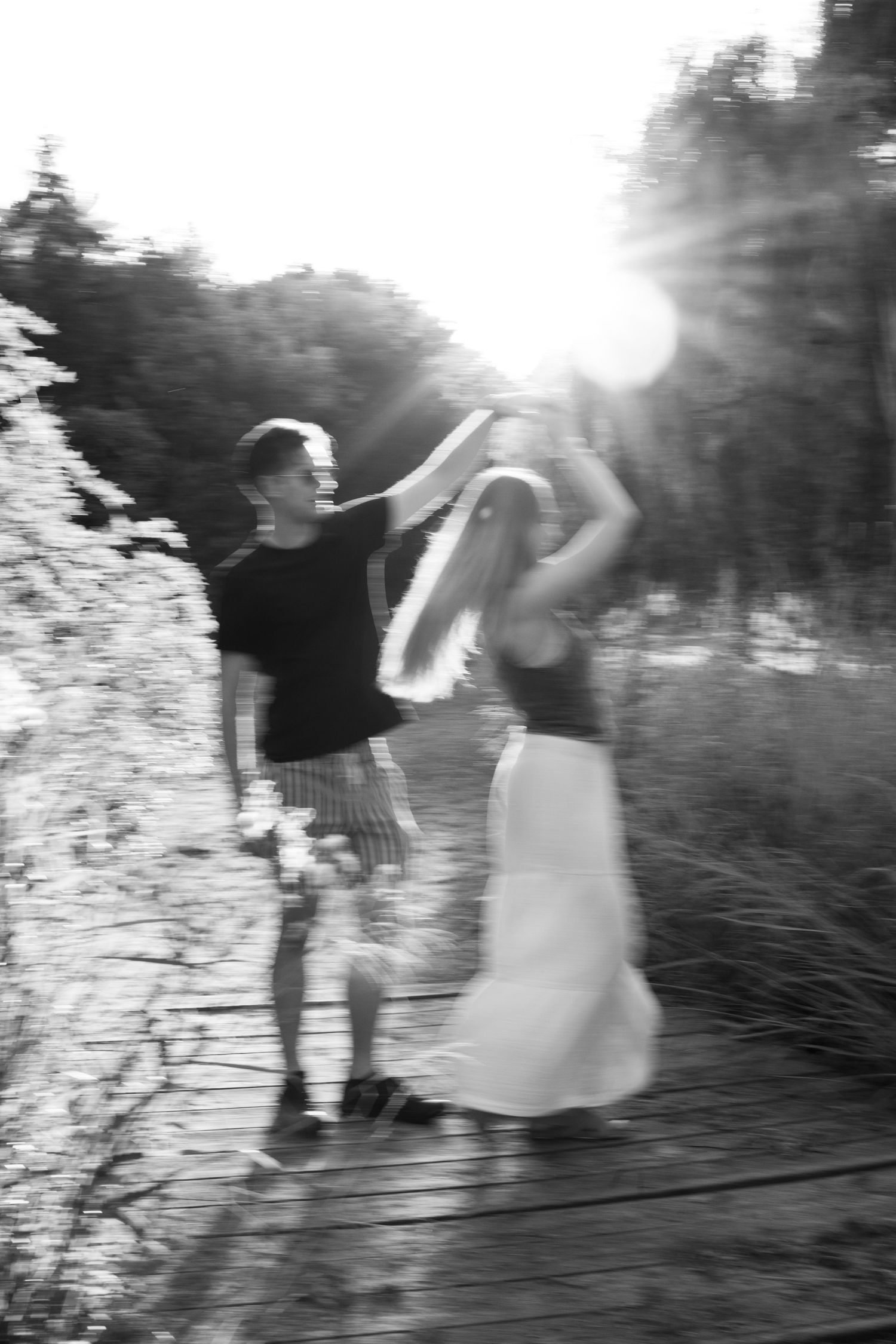 A series of blurry black and white photos showing two people dancing together in an outdoor setting.