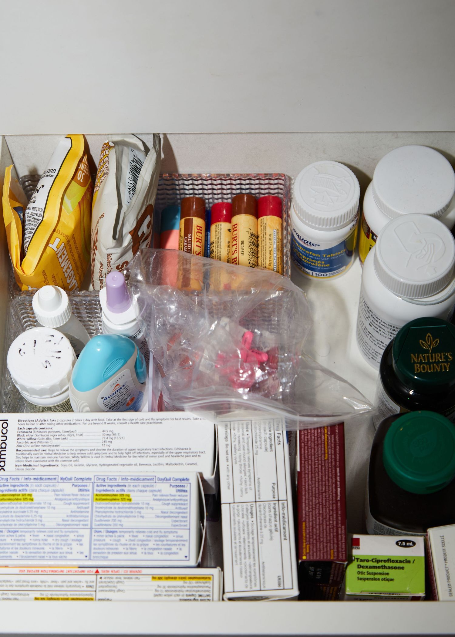 Medical supplies and medications arranged in a storage box with pill bottles and packaging.