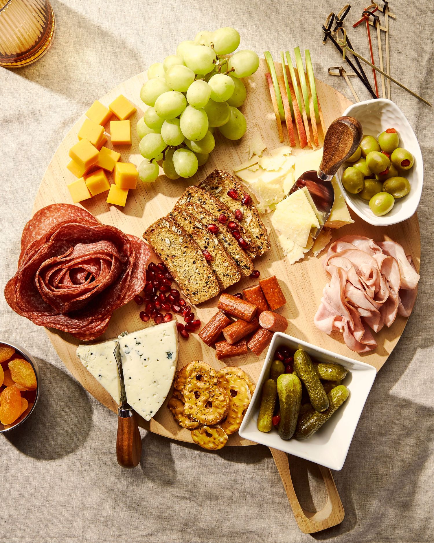 Gourmet charcuterie board with meats, cheeses, grapes, and garnishes arranged on wooden serving platter.