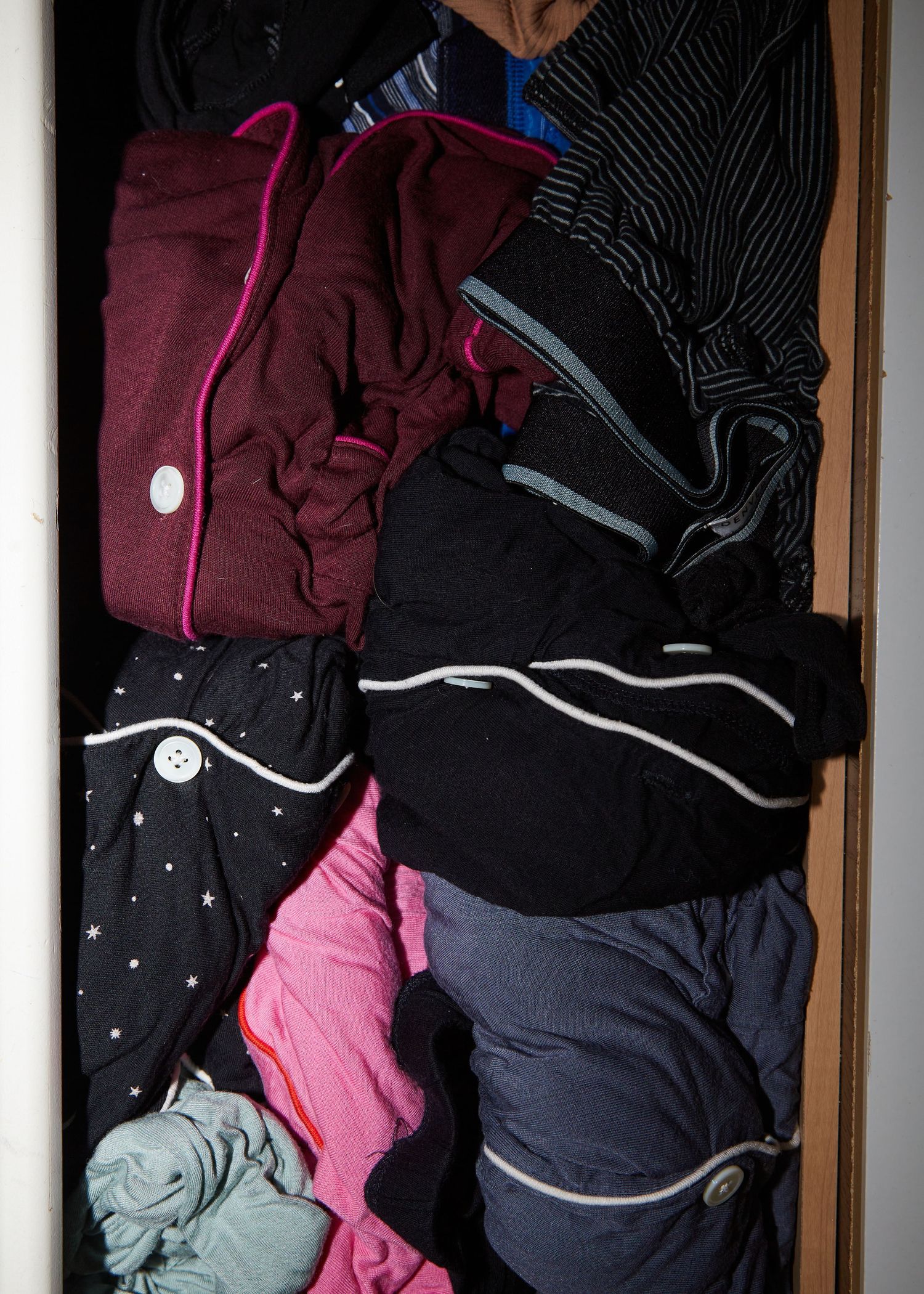 Neatly folded clothing in various colors stored in a drawer.