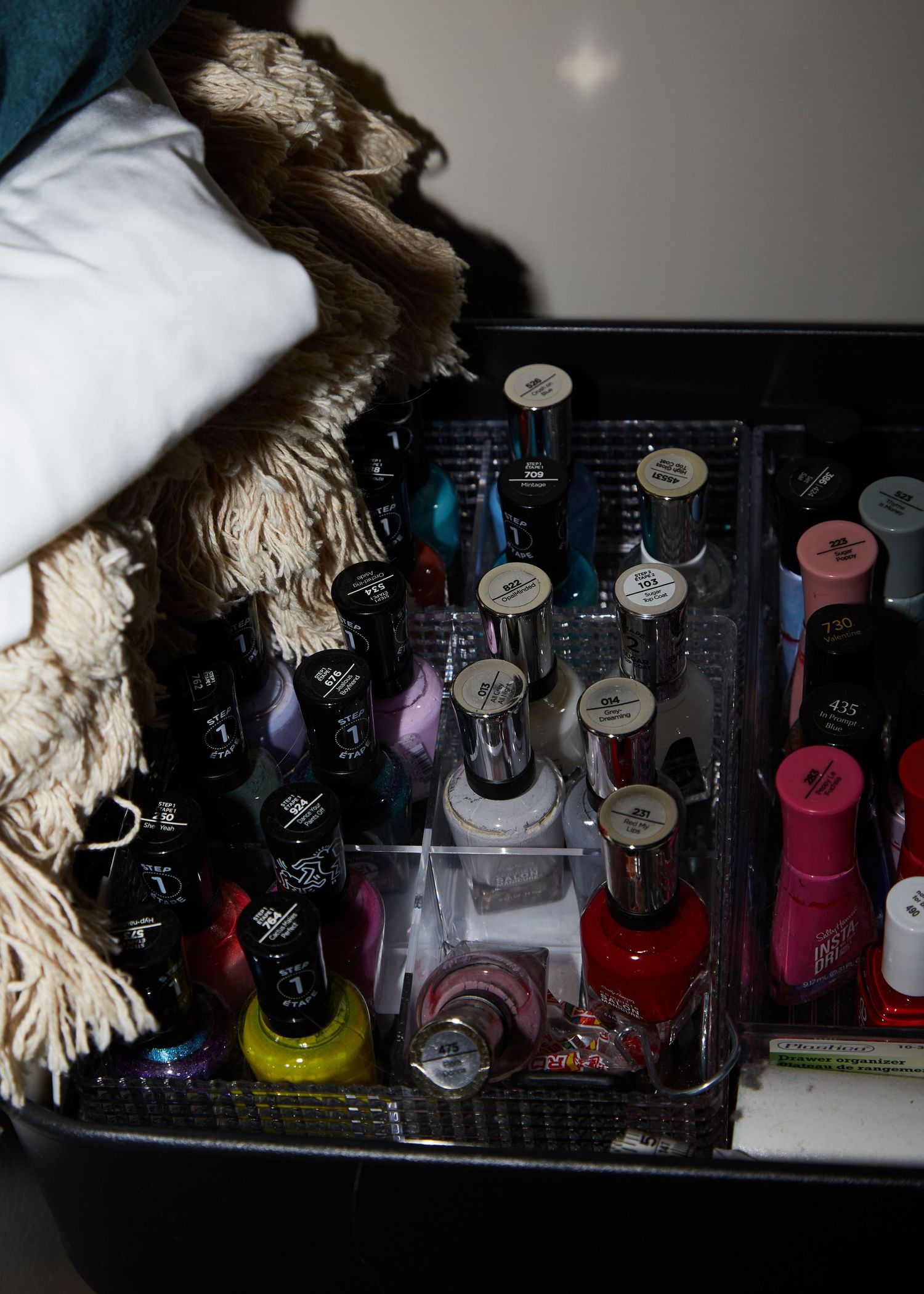 A collection of colorful nail polish bottles arranged in clear storage organizer.