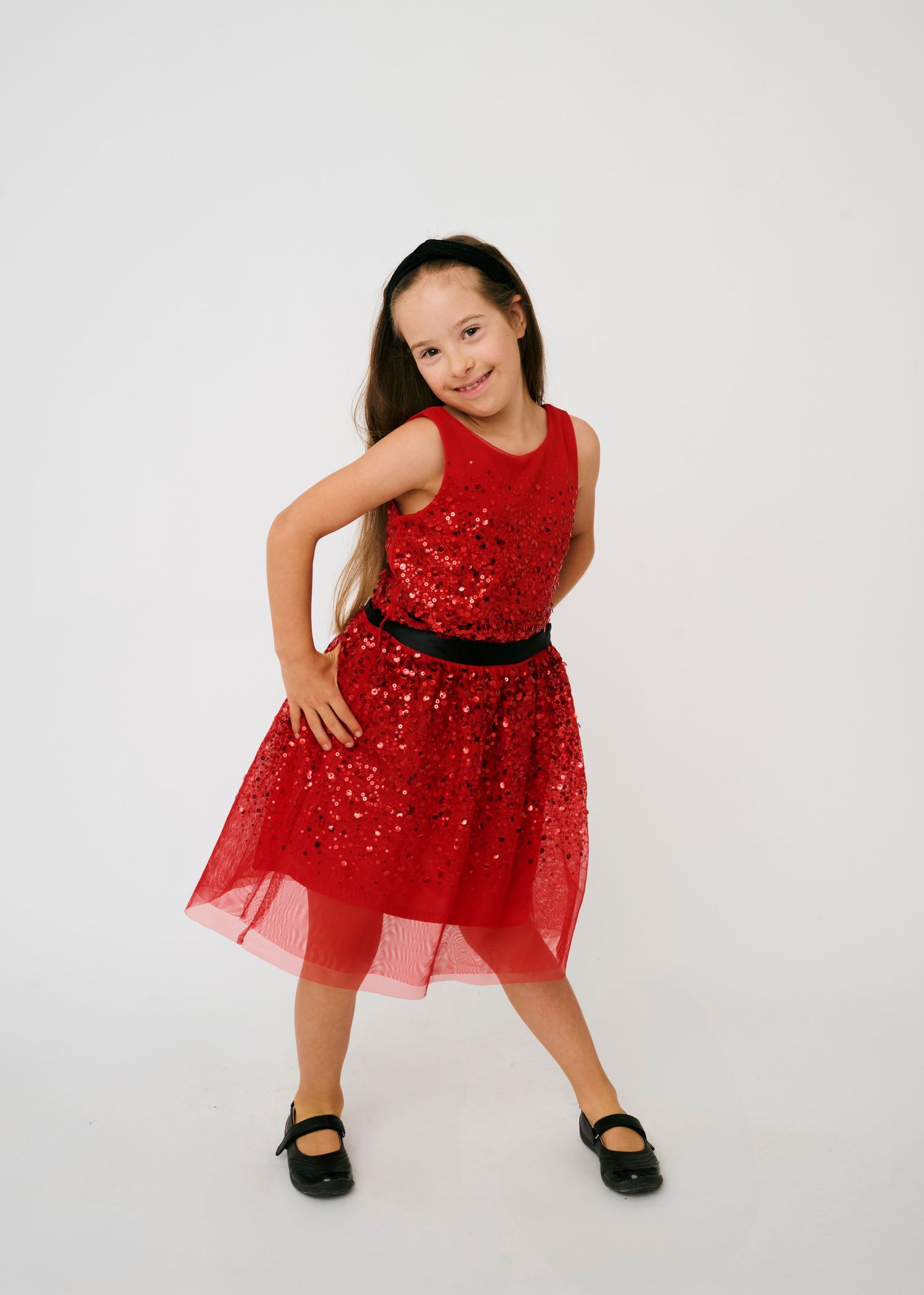 A sequence of four poses showing a sparkly red tulle party dress with black shoes against a white background.