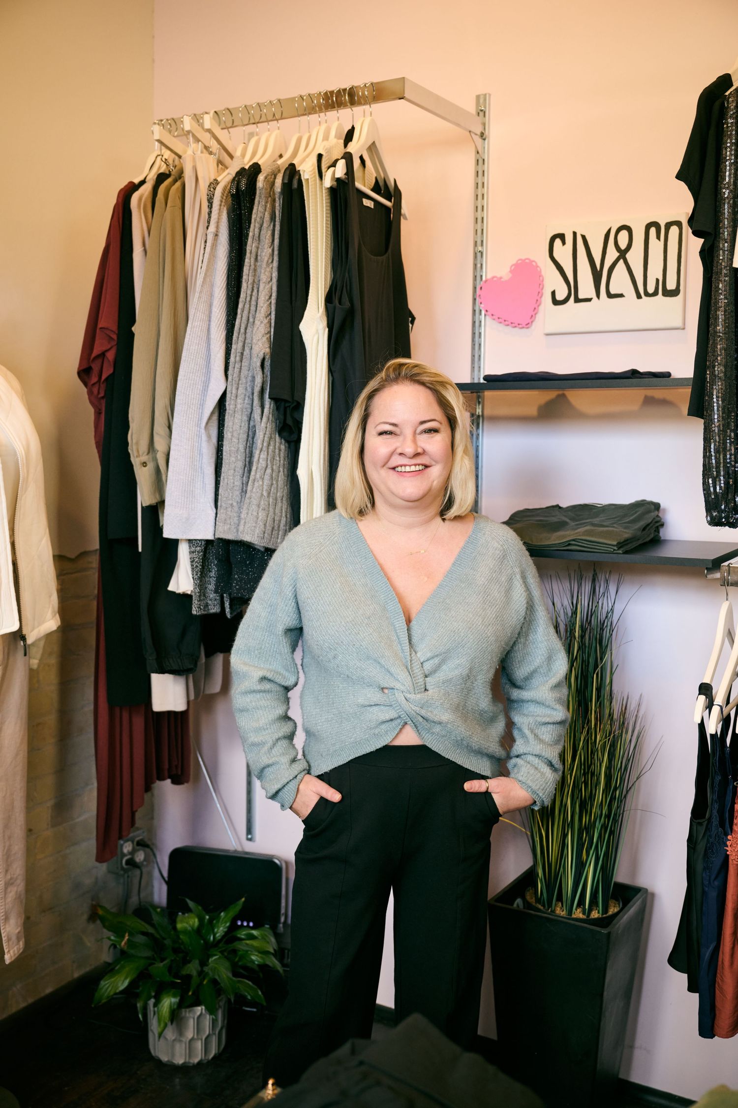 A retail clothing store interior with hanging garments, shelves displaying merchandise, and a pink heart logo that says 'SILVER CO'.