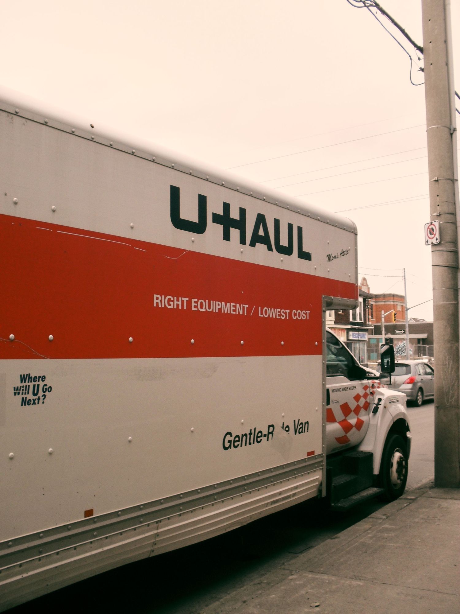 A U-Haul moving truck with orange and white branding parked on a city street.