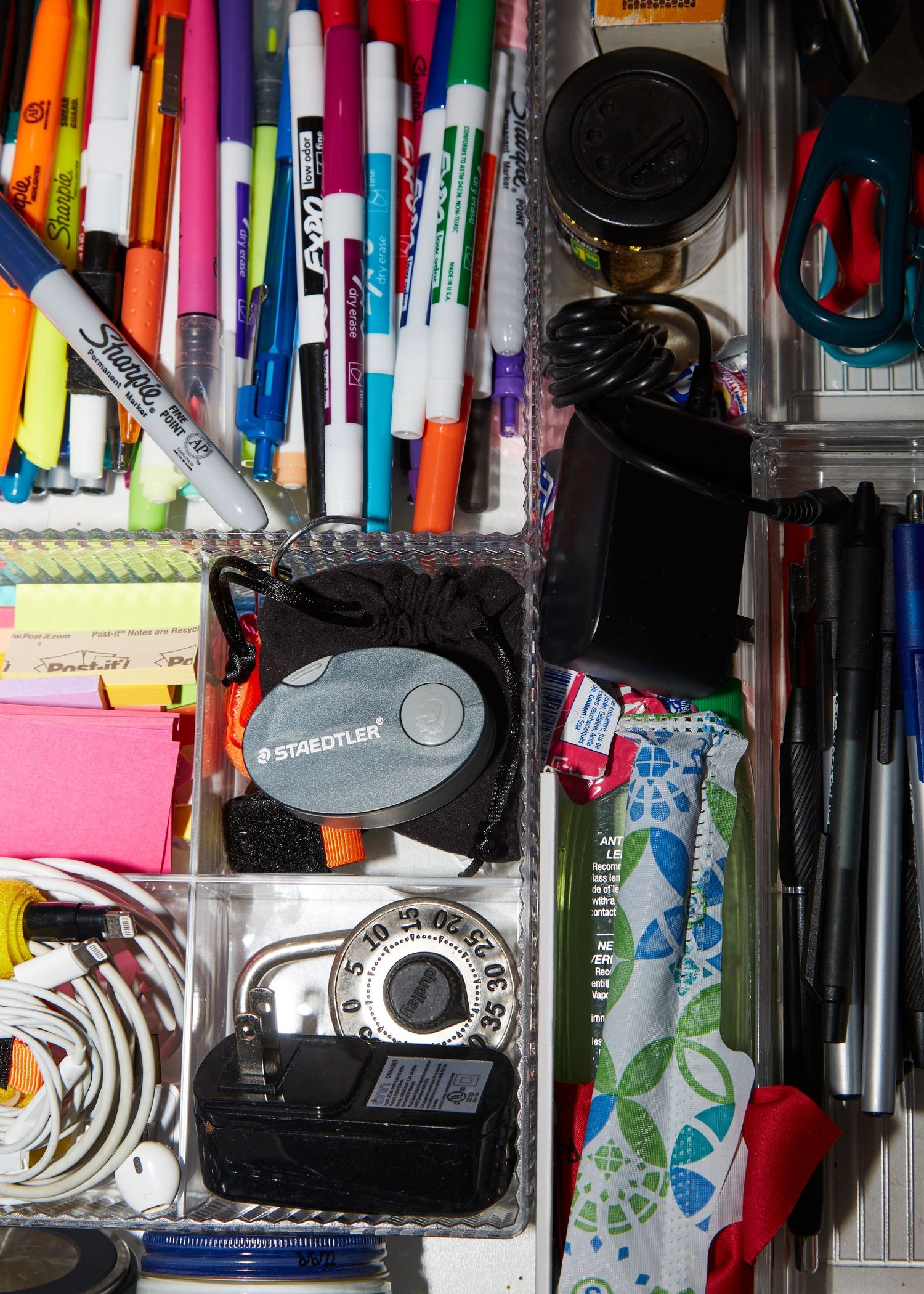 Colorful collection of pens, markers and office supplies organized in a drawer.