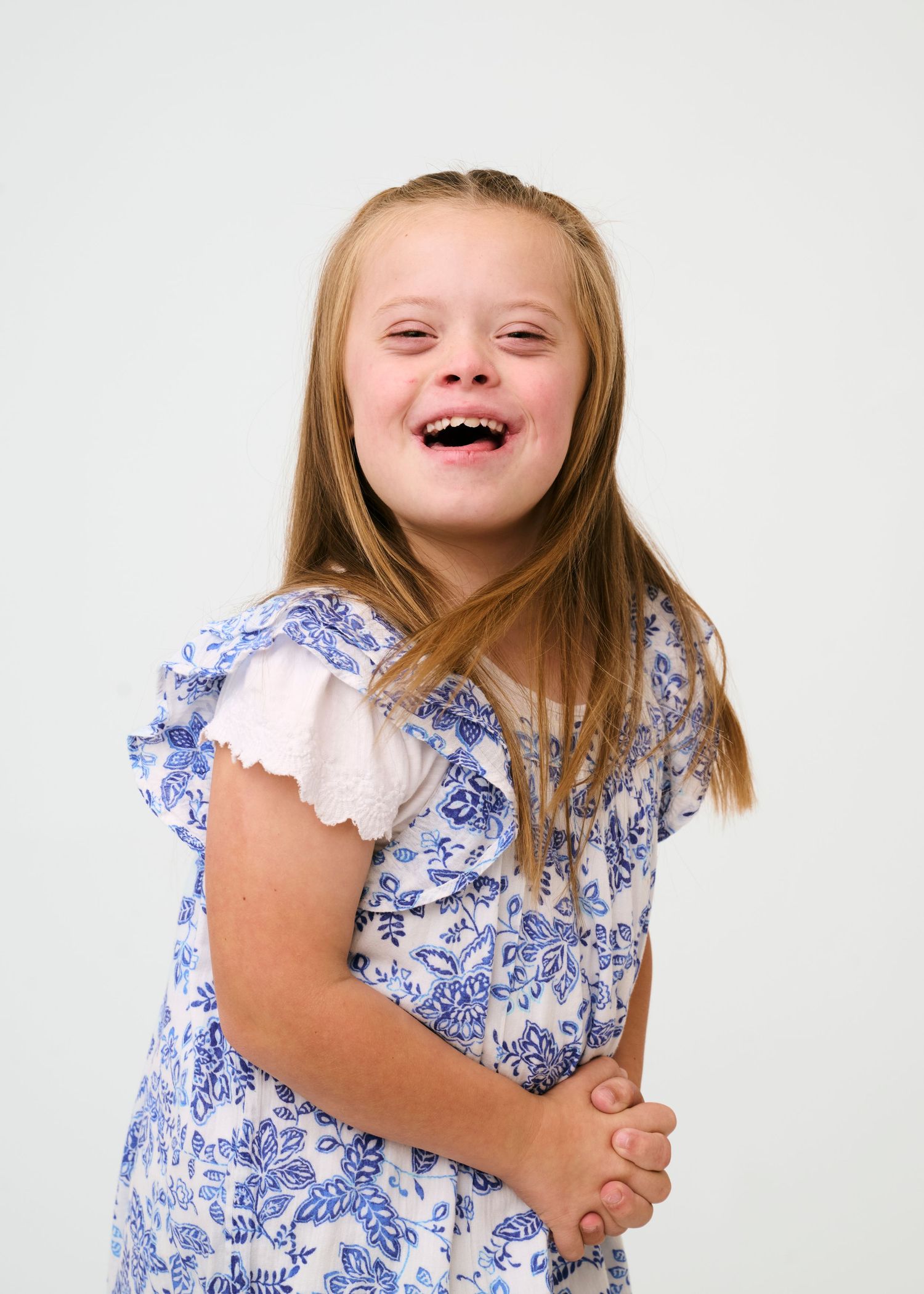 Child wearing blue and white floral dress shows joyful expressions in studio photos.