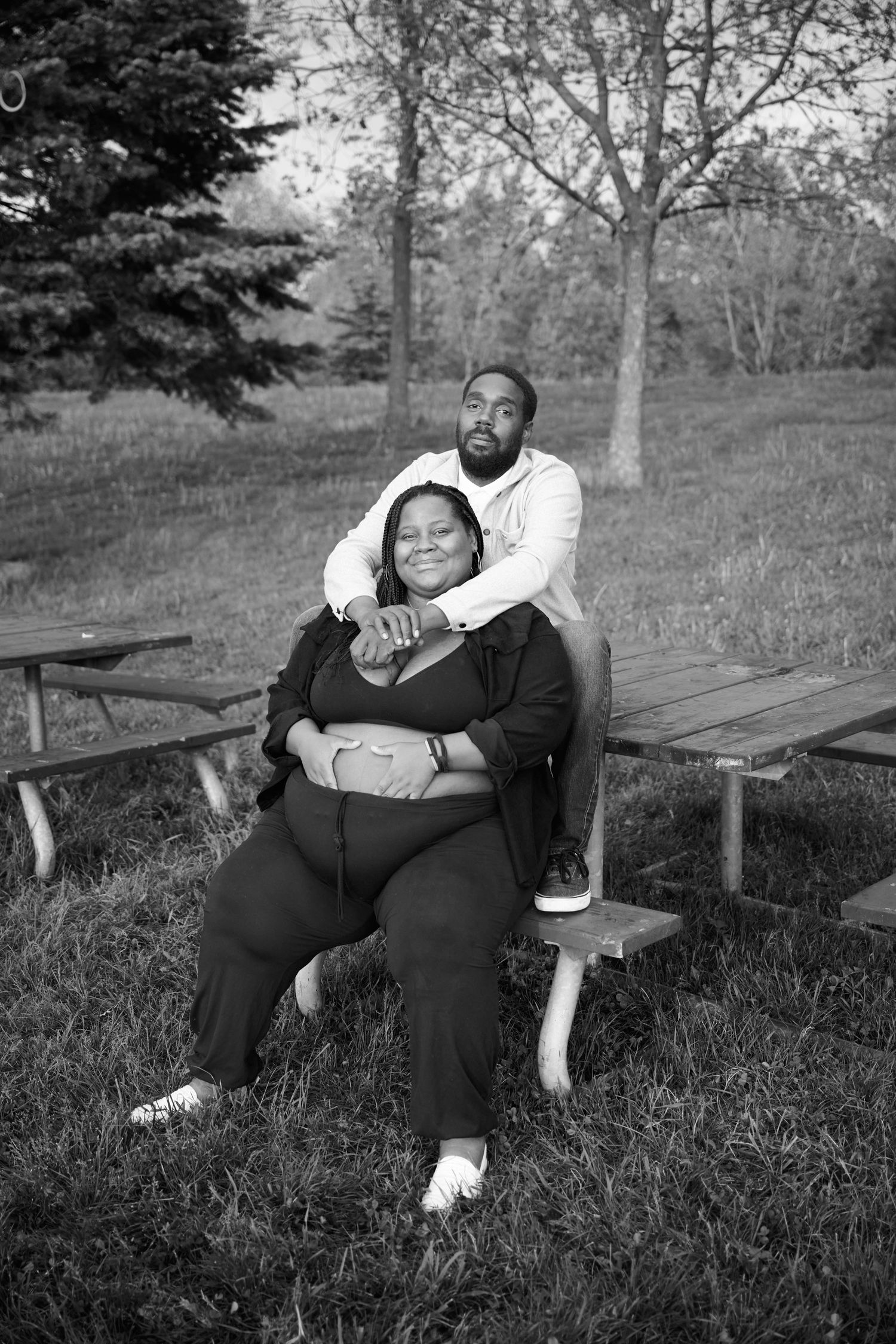 A series of black and white photographs showing a person reclining on a wooden park bench in a grassy outdoor setting.