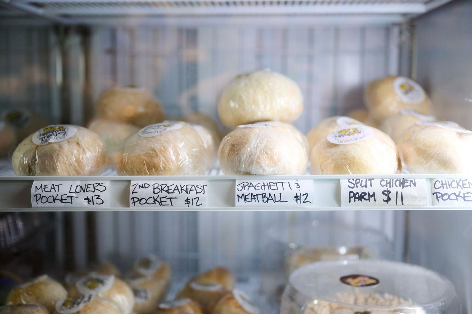 Labeled petri dishes containing sourdough starters lined up on refrigerator shelf.