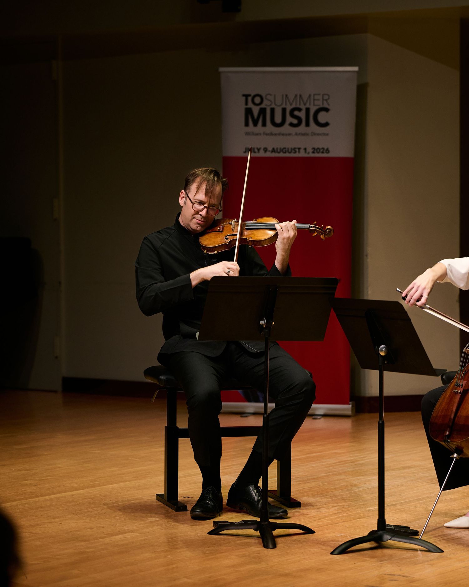 Violinist performing at TO Summer Music festival on stage, seated with music stand, July 2016.