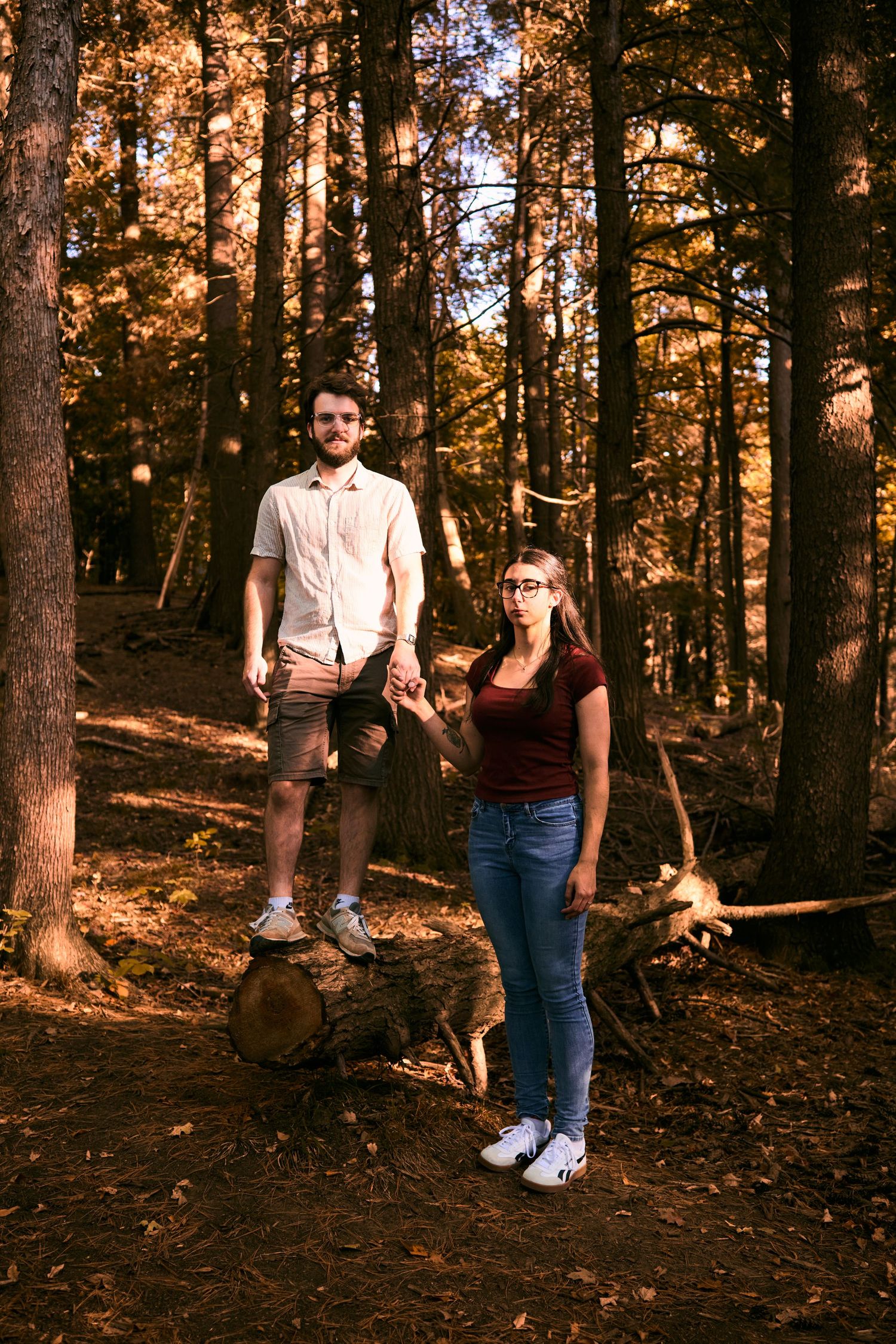 Four sequential photos of a couple standing in a sunlit autumn forest with fallen leaves on the ground.