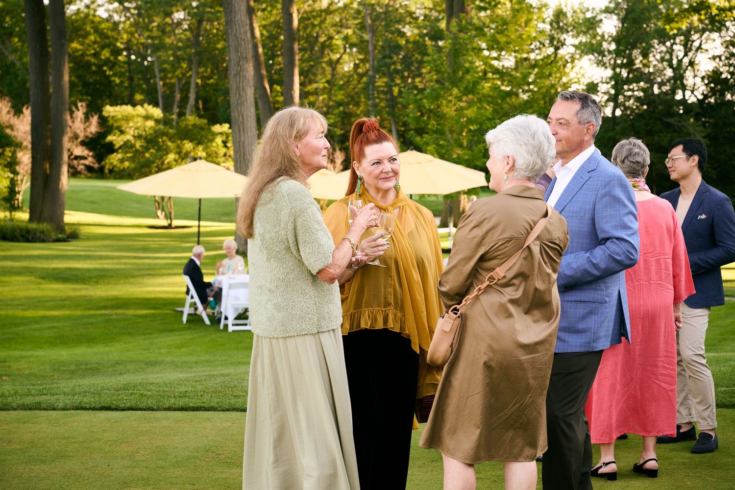 Guests socializing outdoors on a lush green lawn at an elegant garden party event.