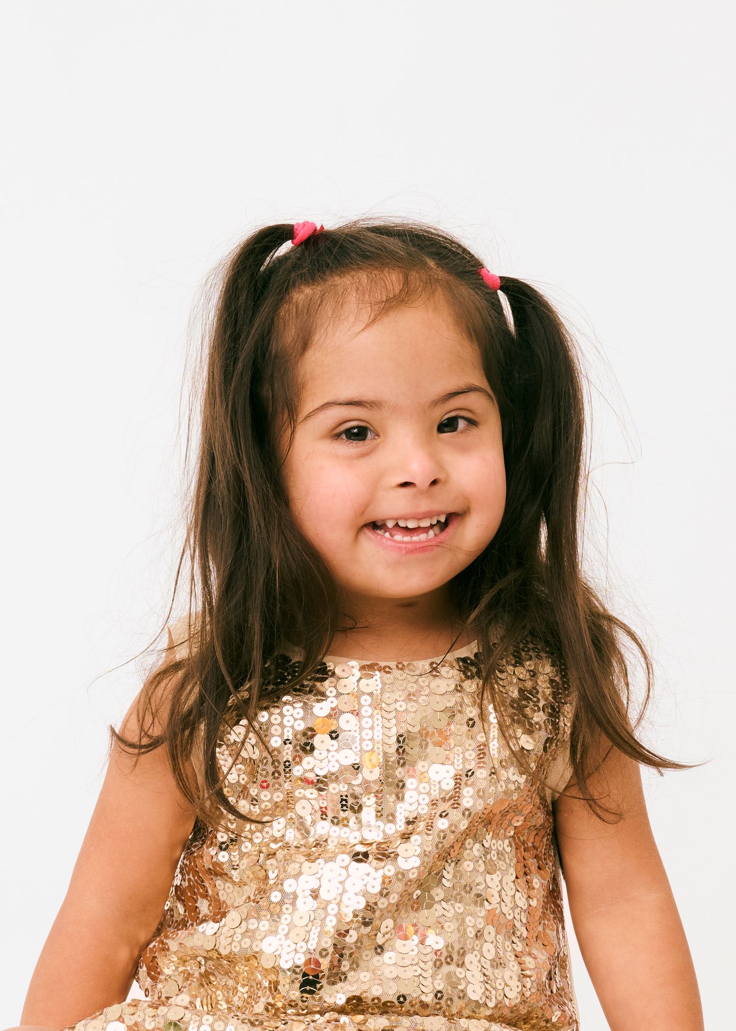 A young child in a sparkly gold dress poses in four similar photos with pigtails and a cheerful expression.