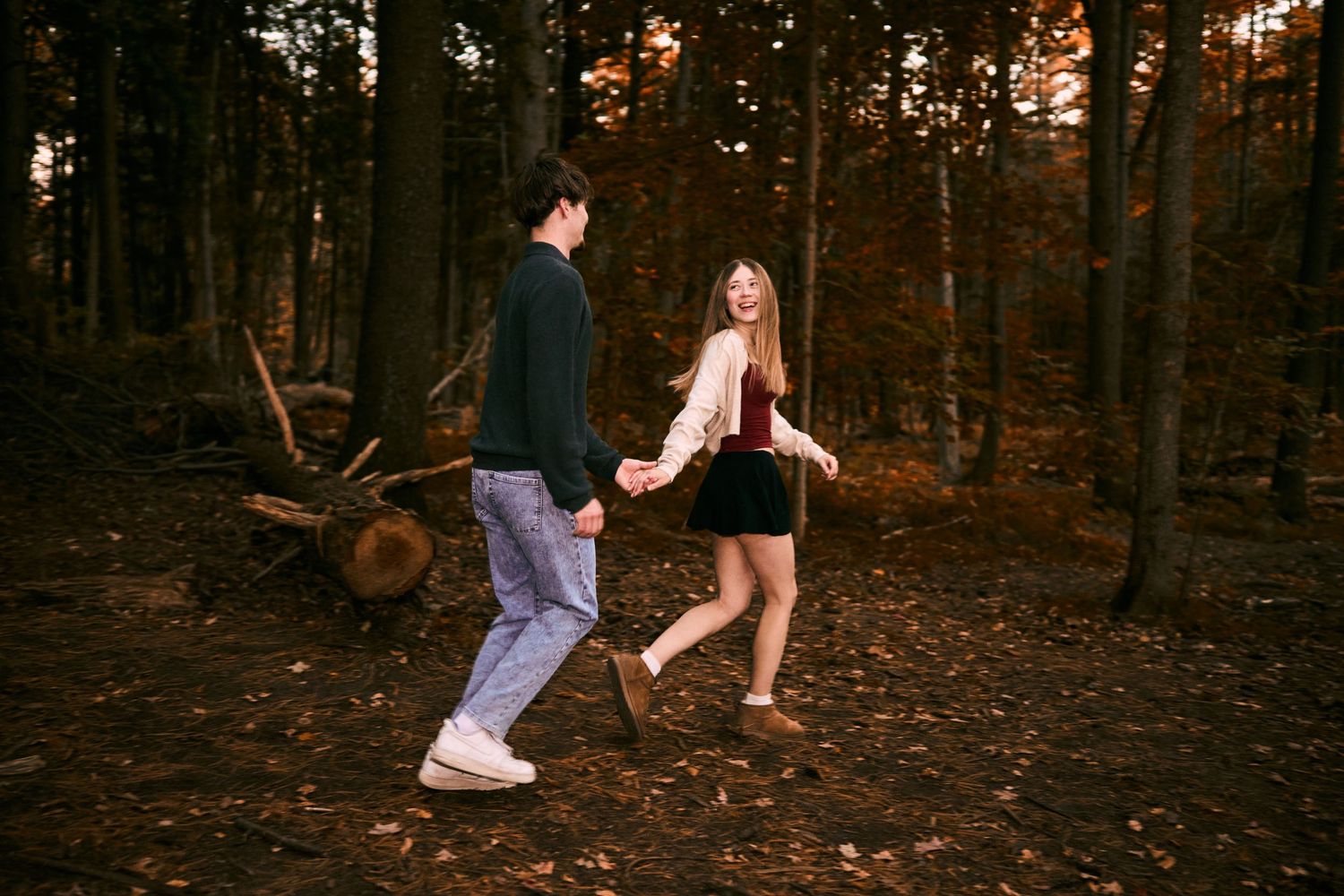 People walking through a forest at sunset with golden light filtering through the trees.