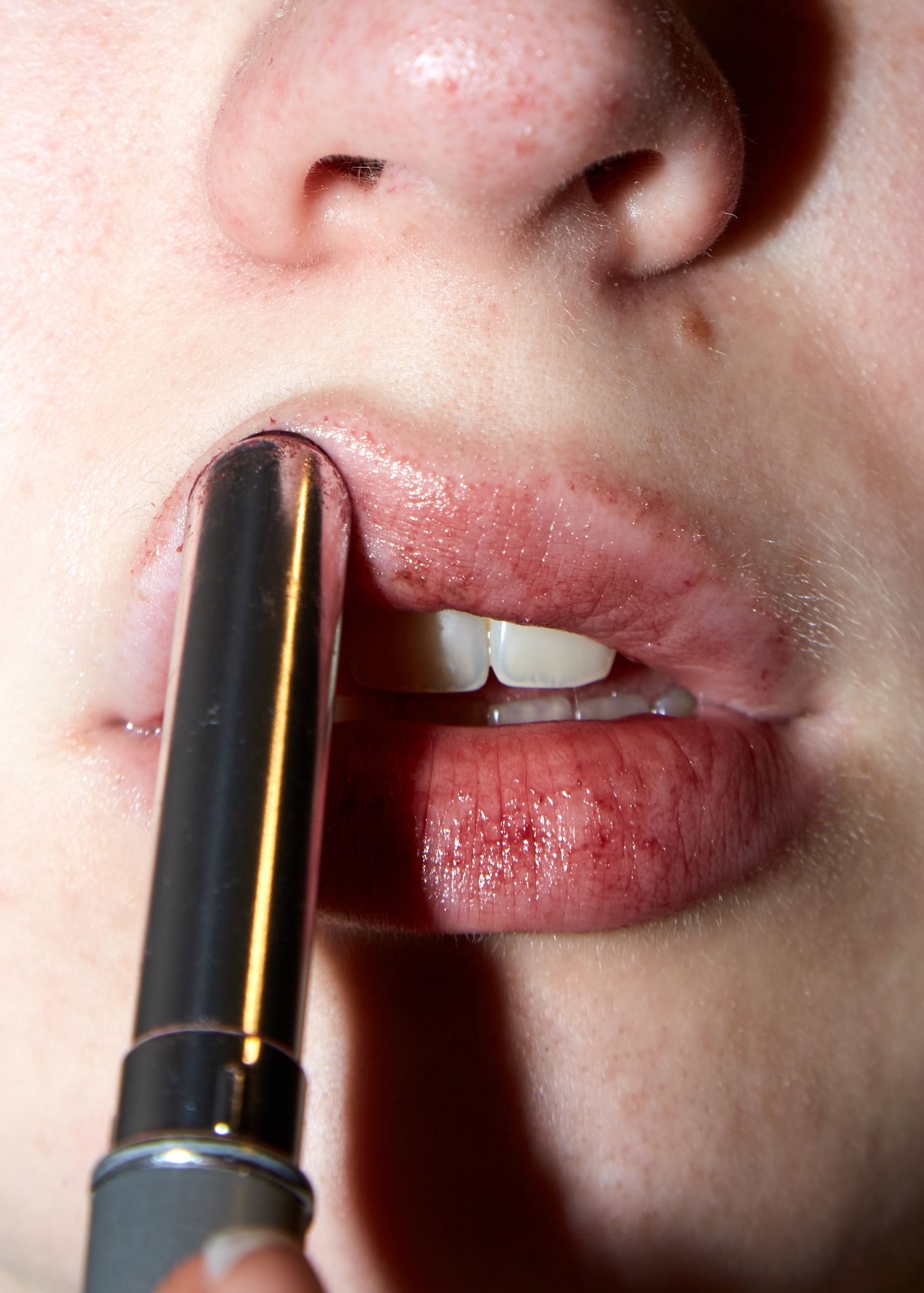 Close-up of applying dark lipstick to lips.