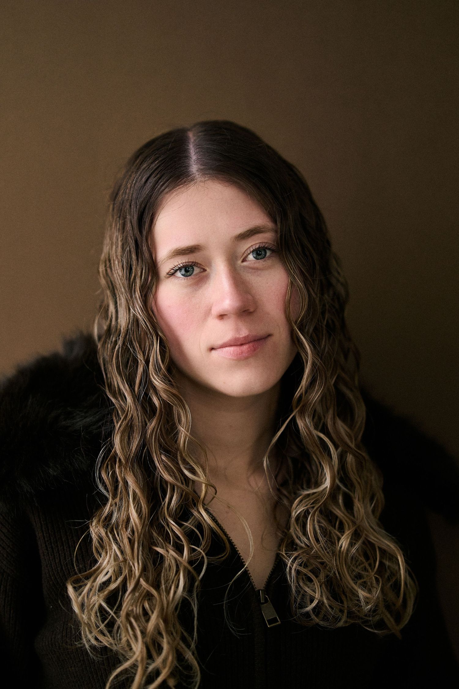 Portrait series with dark background showing long wavy brown hair and soft lighting creating a moody atmosphere.
