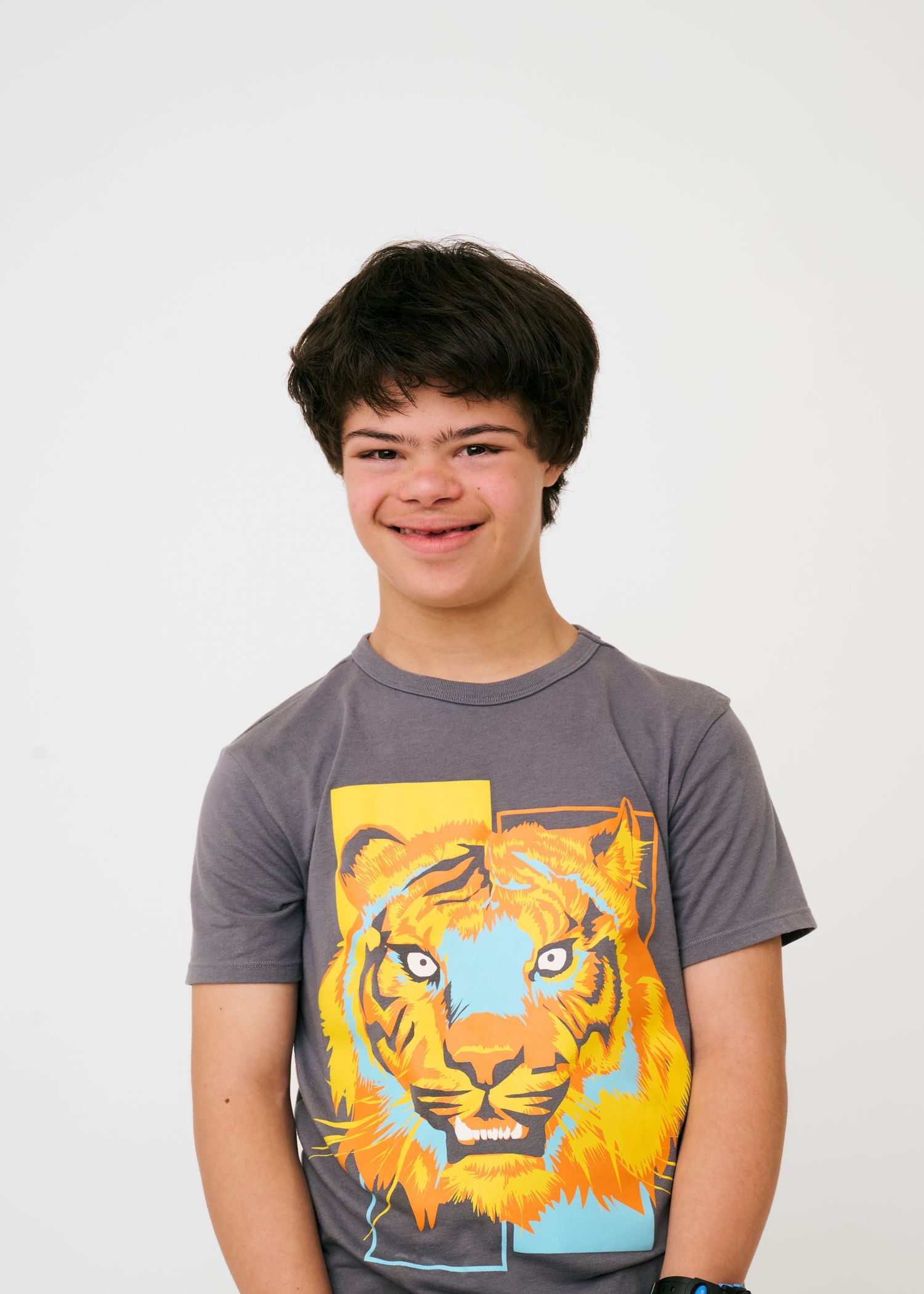 Person wearing grey t-shirt with tiger graphic poses against white background.