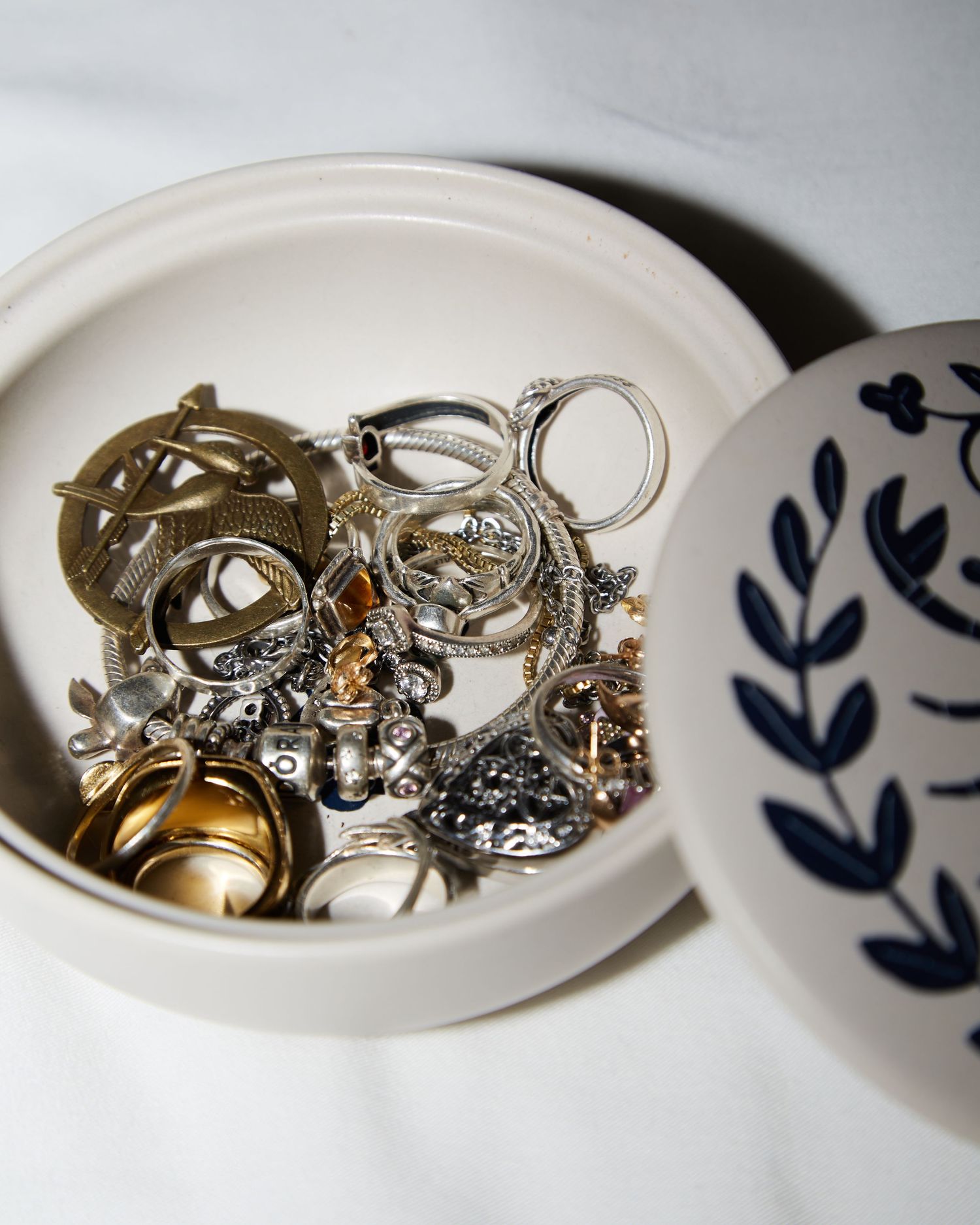 Decorative ceramic dish containing assorted rings and jewelry pieces.