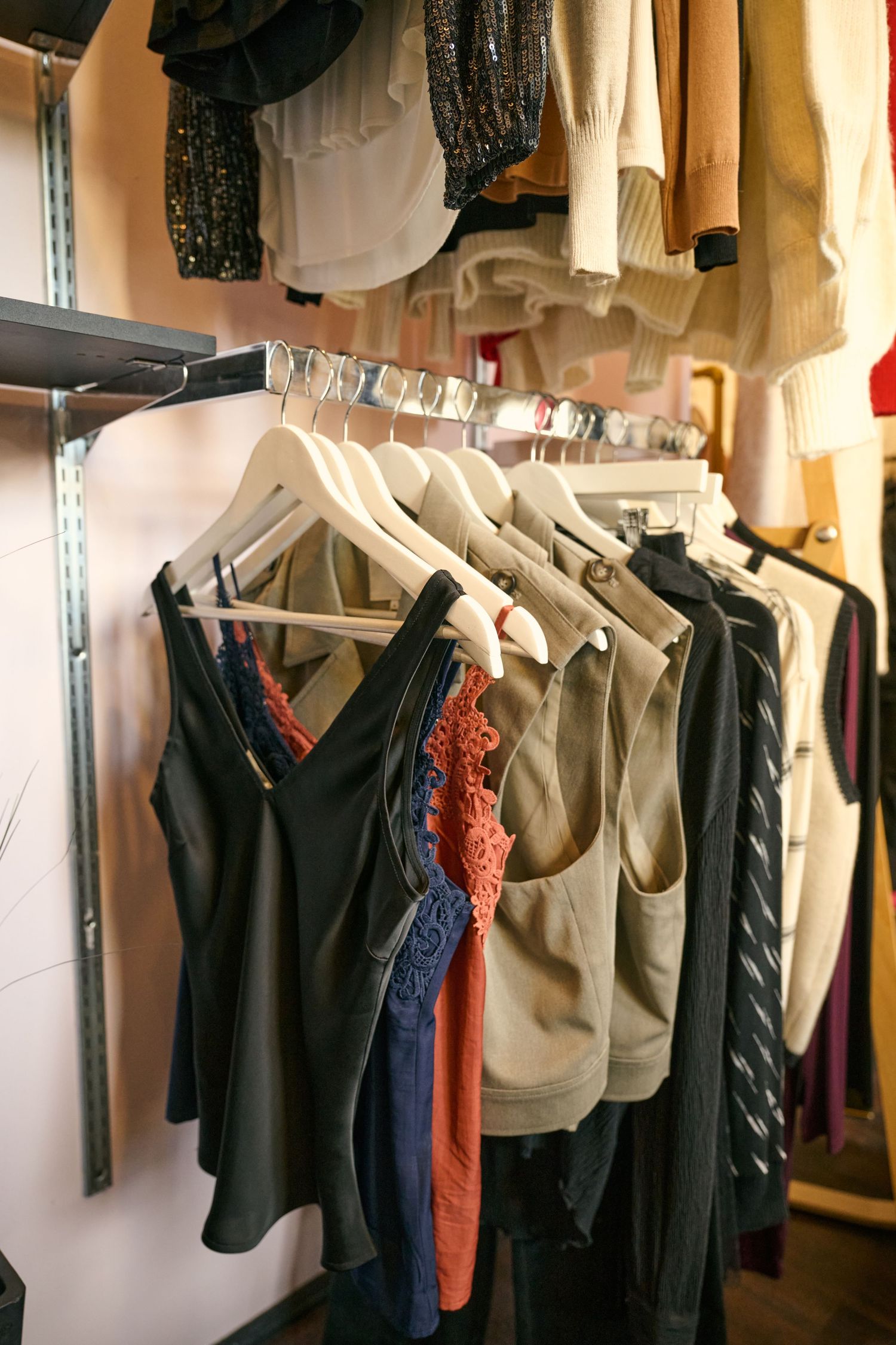 Organized closet rack displaying various clothing items on white hangers against light wall.