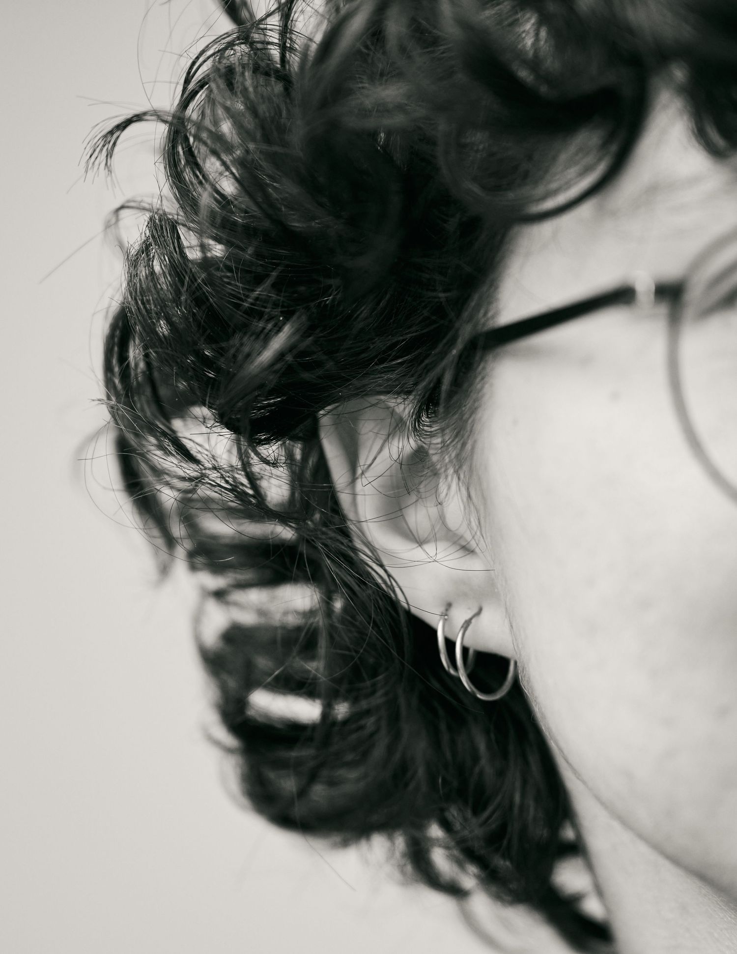 Black and white close-up of curly dark hair and glasses in profile.