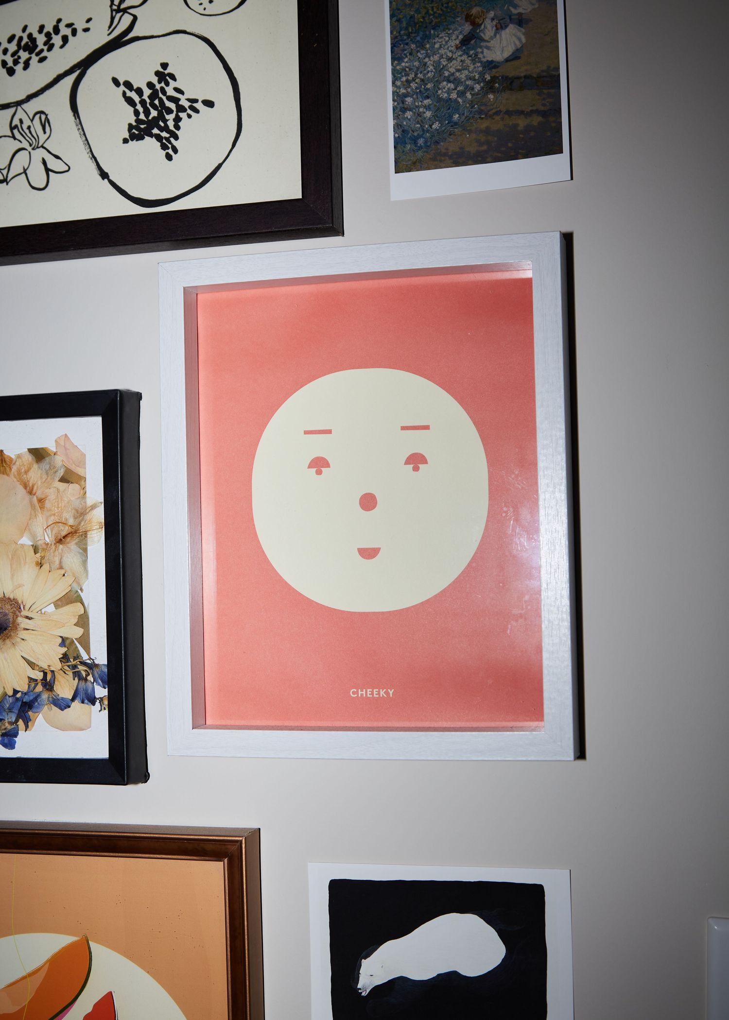A minimalist art print featuring a simple white circular face design on a coral pink background.