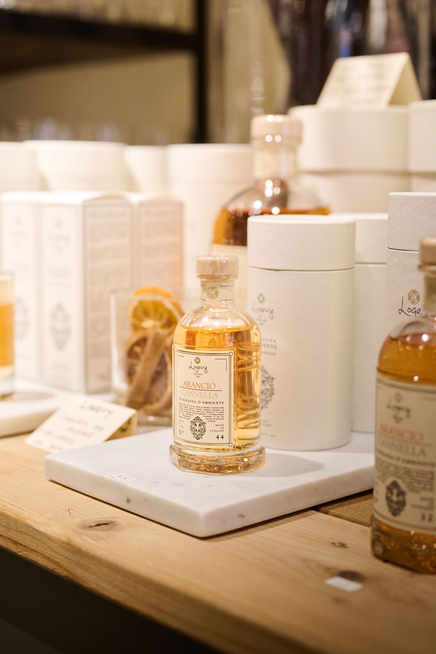 Elegant glass bottles of fragrance and perfume products displayed with white packaging boxes on wooden surface.