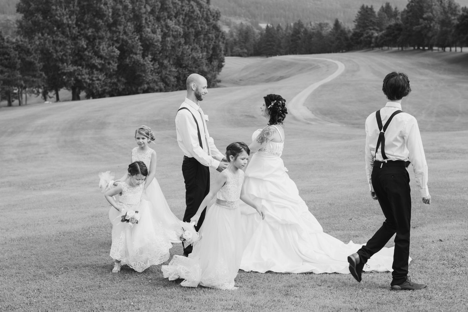 A wedding party walks together across a scenic hillside golf course.