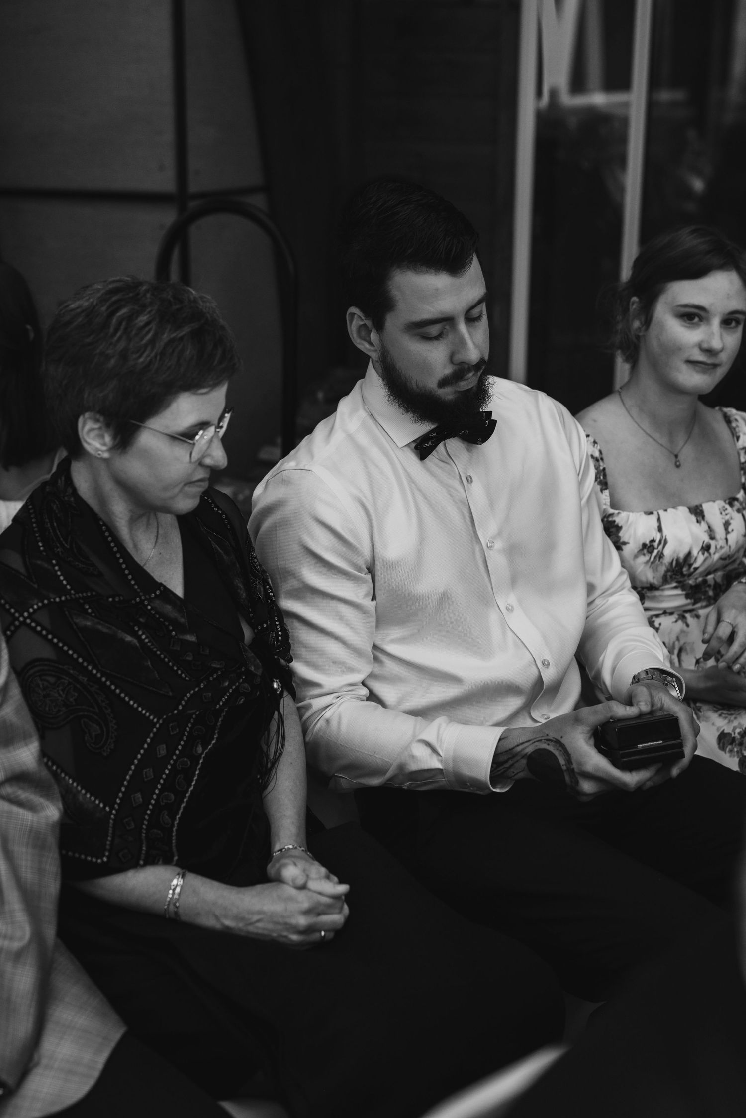 Wedding guests looking at phones while seated during reception.