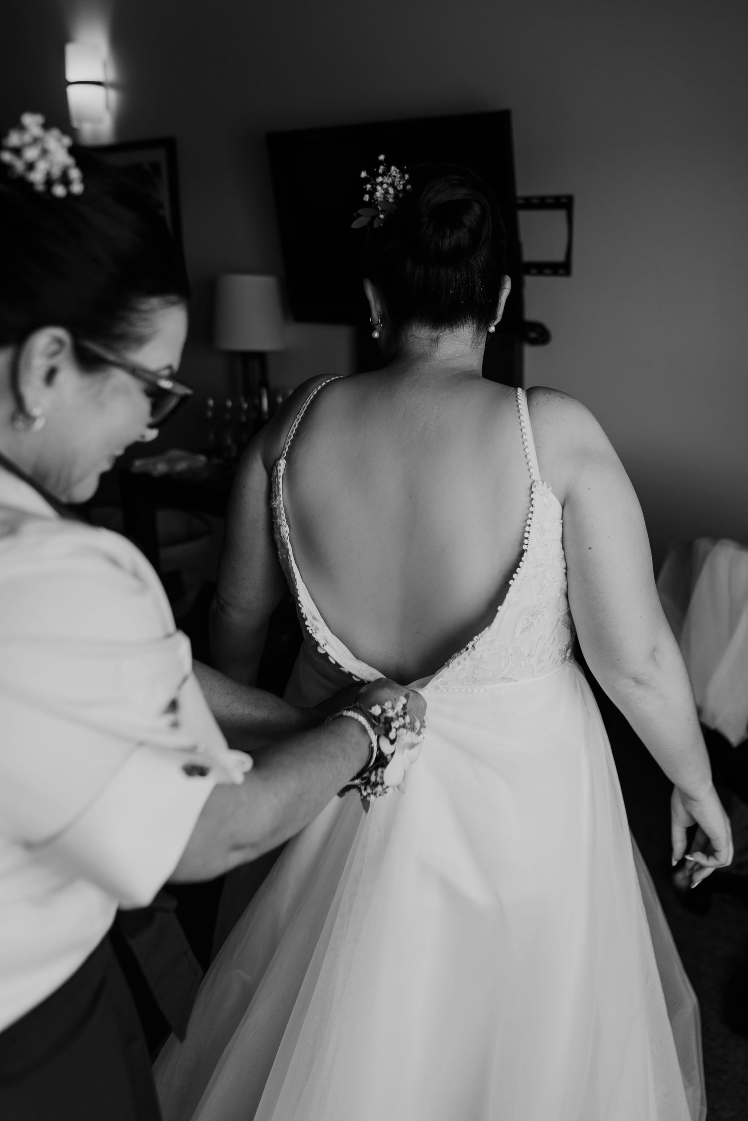 Black and white photo showing final wedding dress adjustments being made.