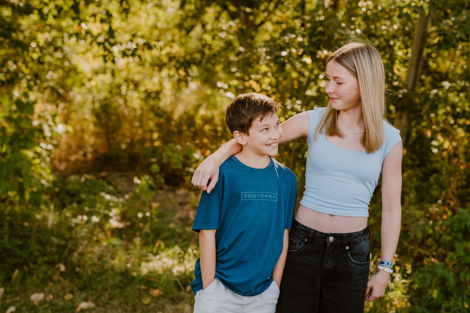 Une fratrie de deux partage un moment spontané et authentique, dans un décor d'été lumineux.