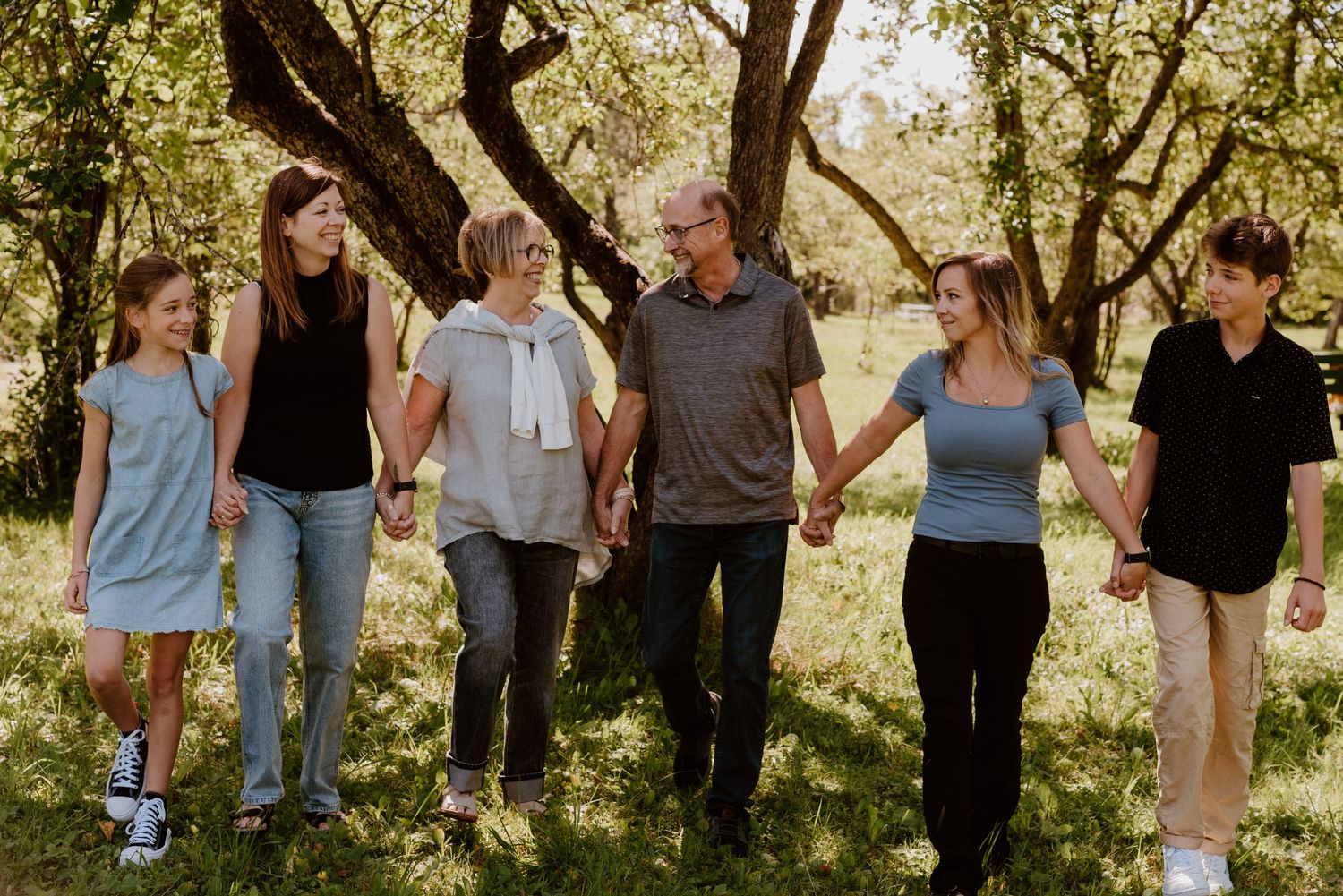 Dans un décor chaleureux, verdoyant et naturel, les membres d'une famille se regardent, main dans la main, complices.