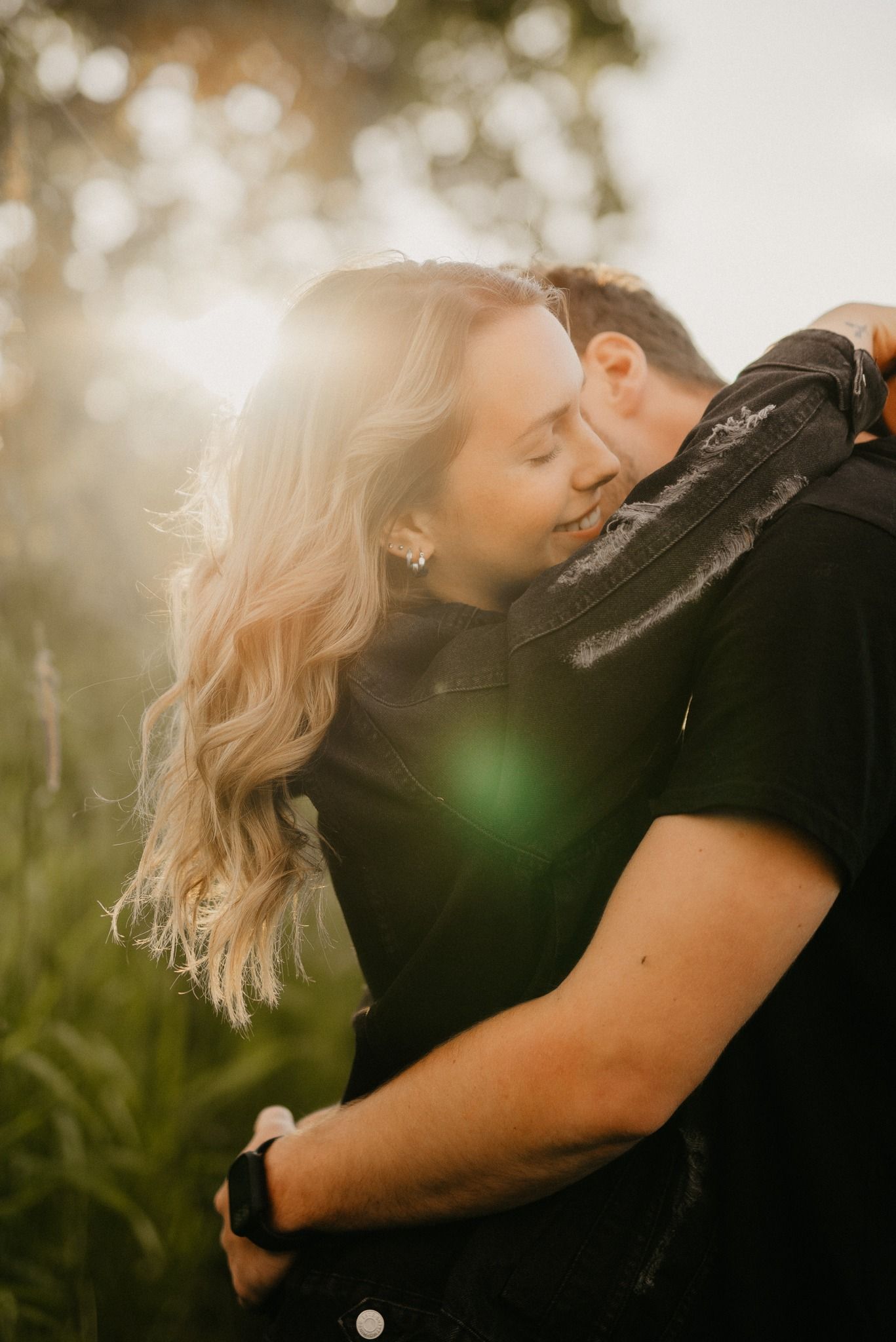 A romantic golden hour portrait of a couple embracing in a sun-drenched outdoor setting.