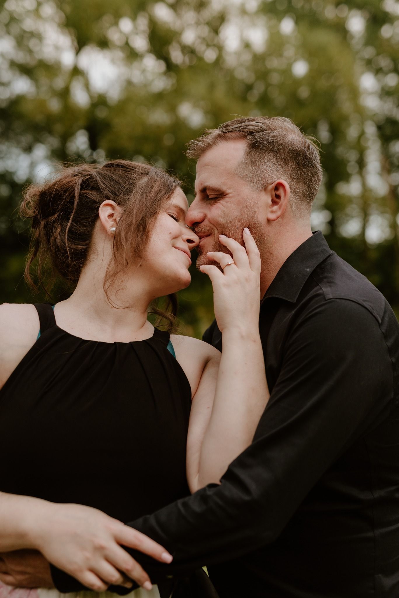 Tender romantic moment captured between couple in casual formal wear outdoors.
