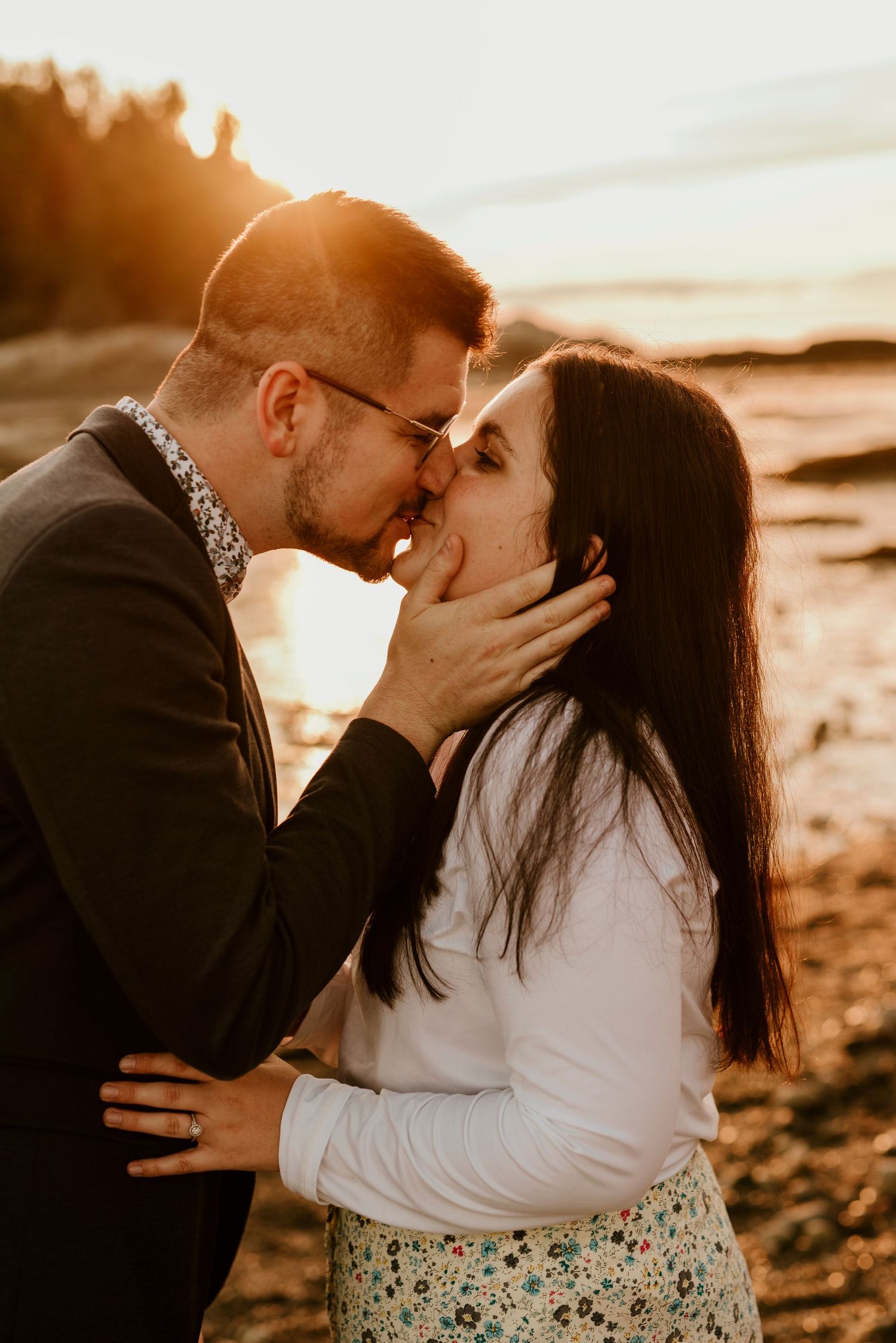 Romantic sunset beach engagement photo with couple sharing tender moment.