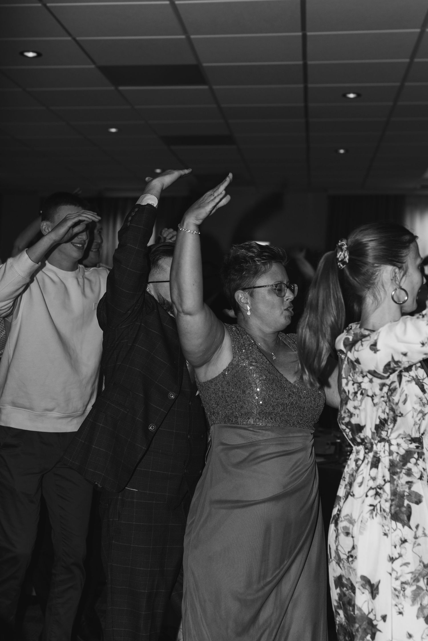 Wedding guests dancing with raised arms in celebration at a reception party.