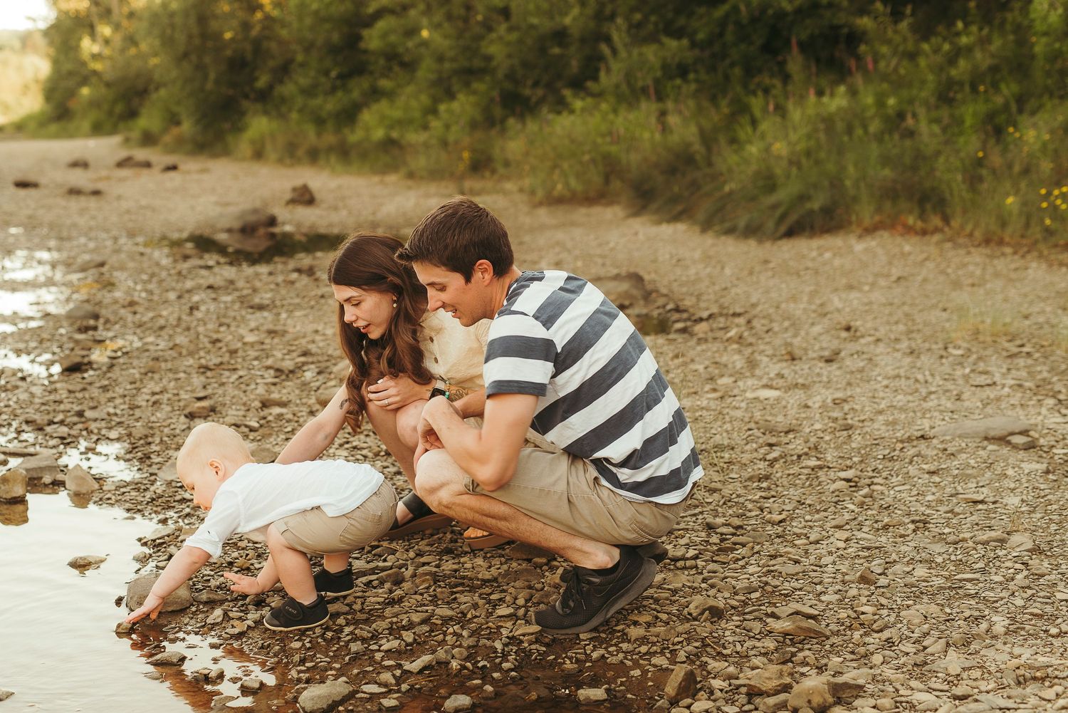 Children play and explore along a rocky beach shoreline on a sunny summer day.