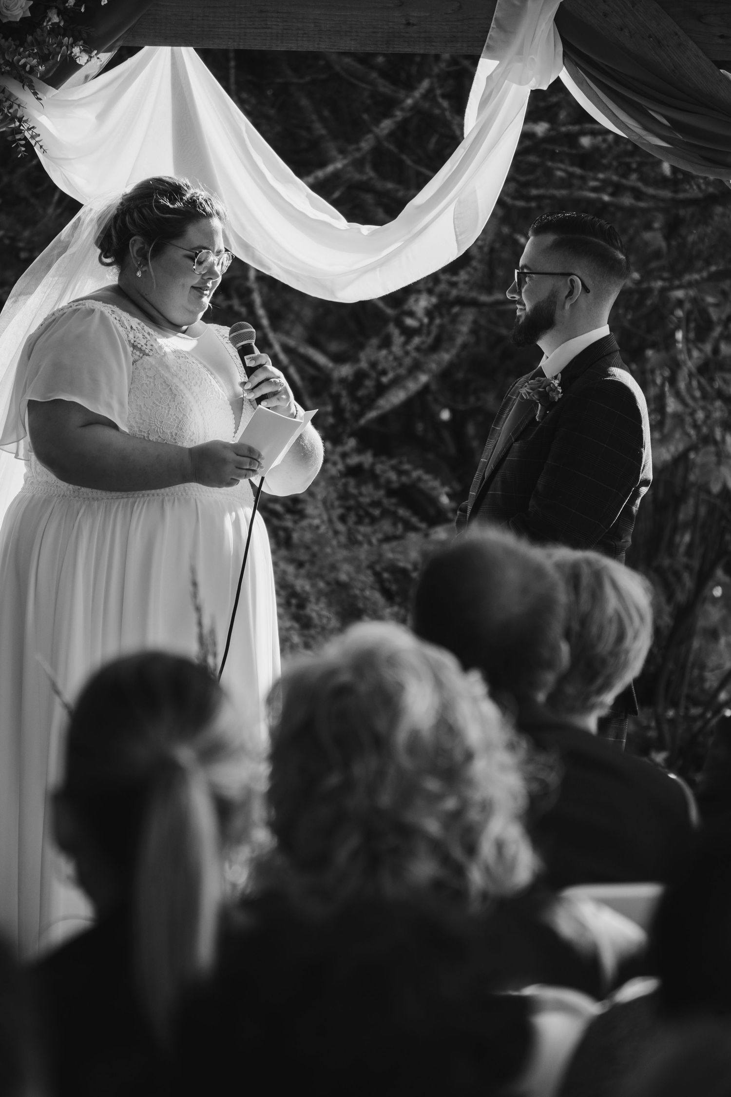 Bride speaking into microphone during outdoor wedding ceremony.