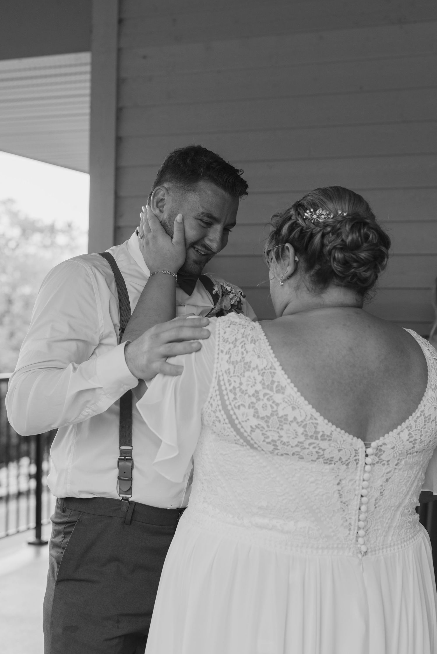 Couple shares emotional first look moment on porch during wedding day.