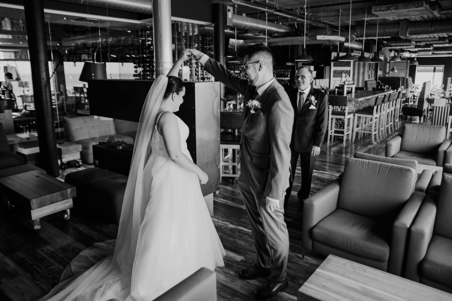 Black and white photo of wedding ceremony in modern industrial-style venue.