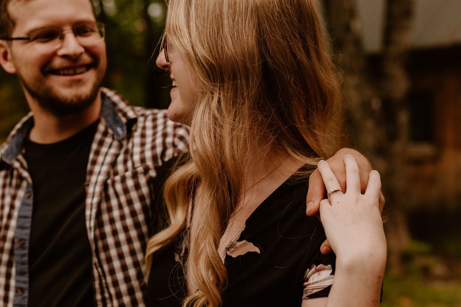 Engaged couple sharing a joyful moment together against natural outdoor backdrop.