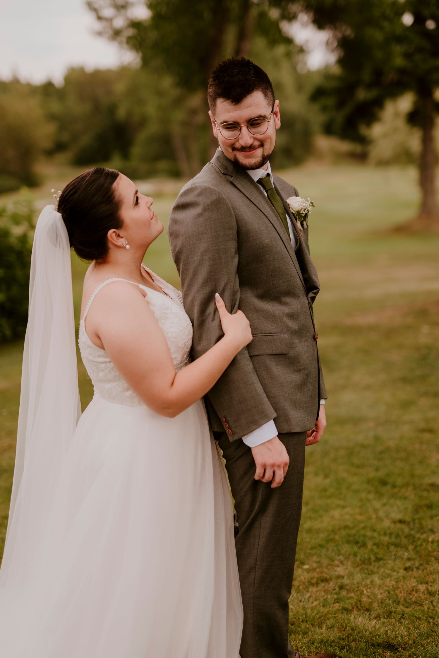 Newlyweds share a romantic moment in a sunlit outdoor garden setting.