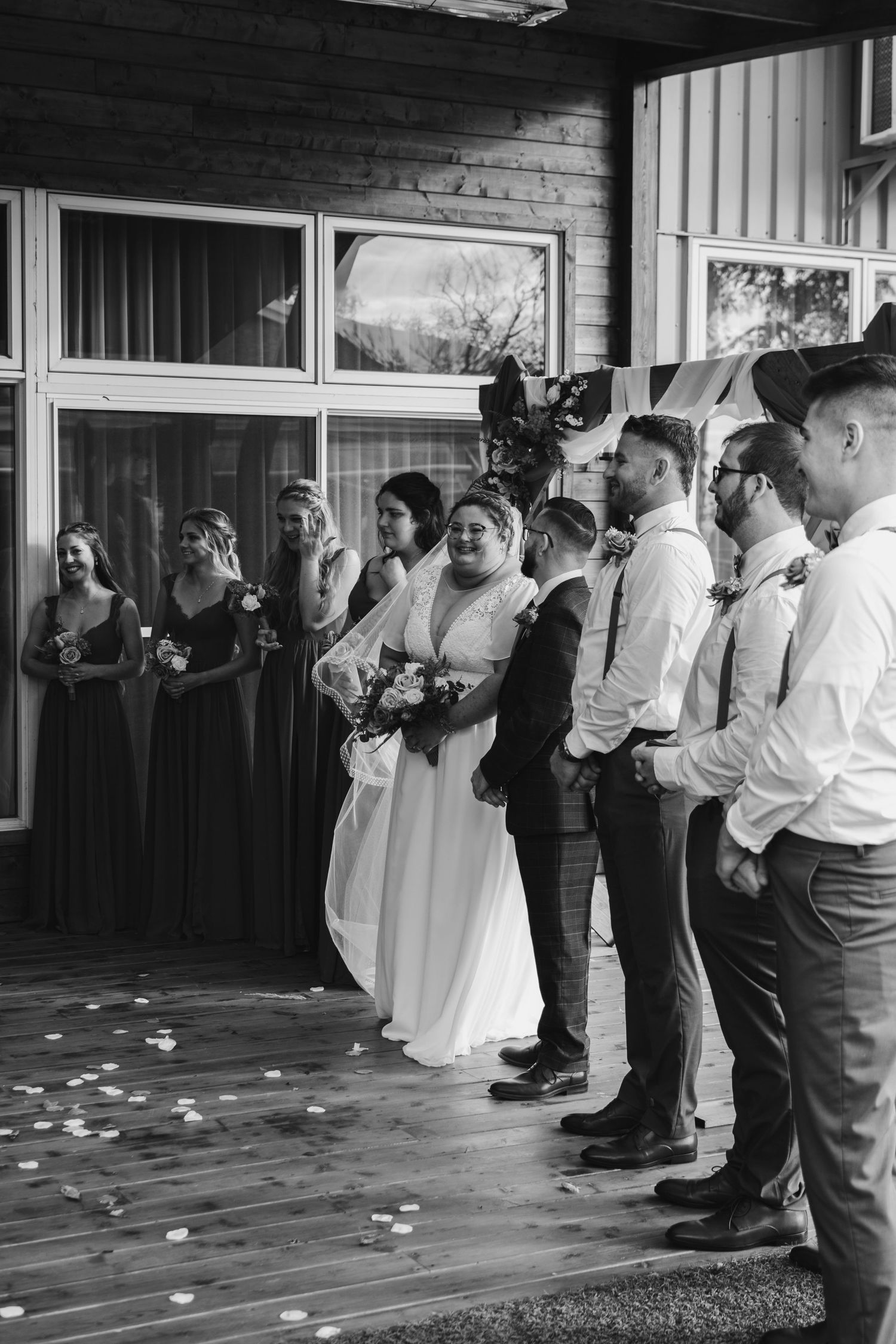 Wedding party lined up for ceremony with bridesmaids and groomsmen in formal attire.