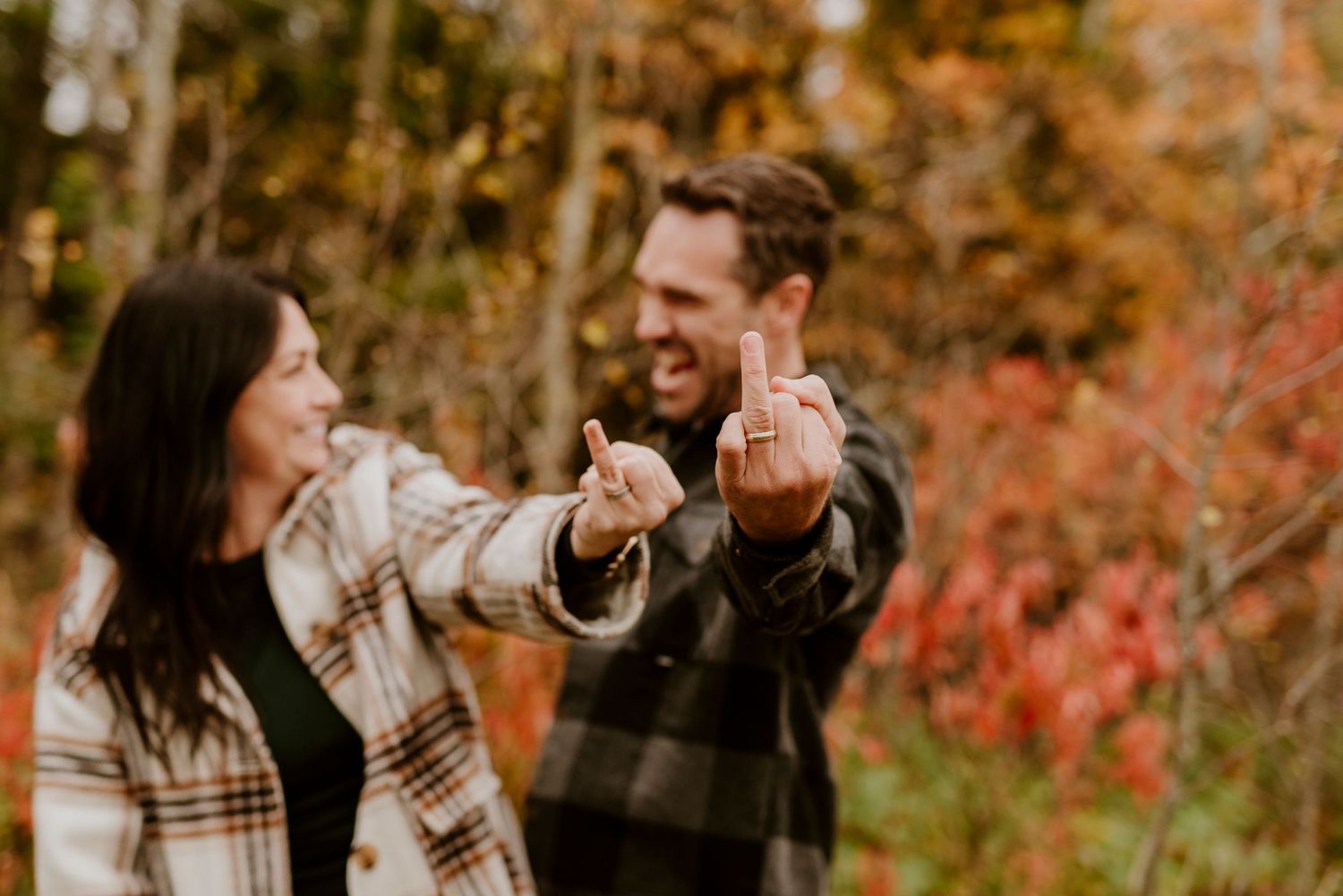 Romantic couple dancing and smiling together in autumn foliage with warm sunlit colors.