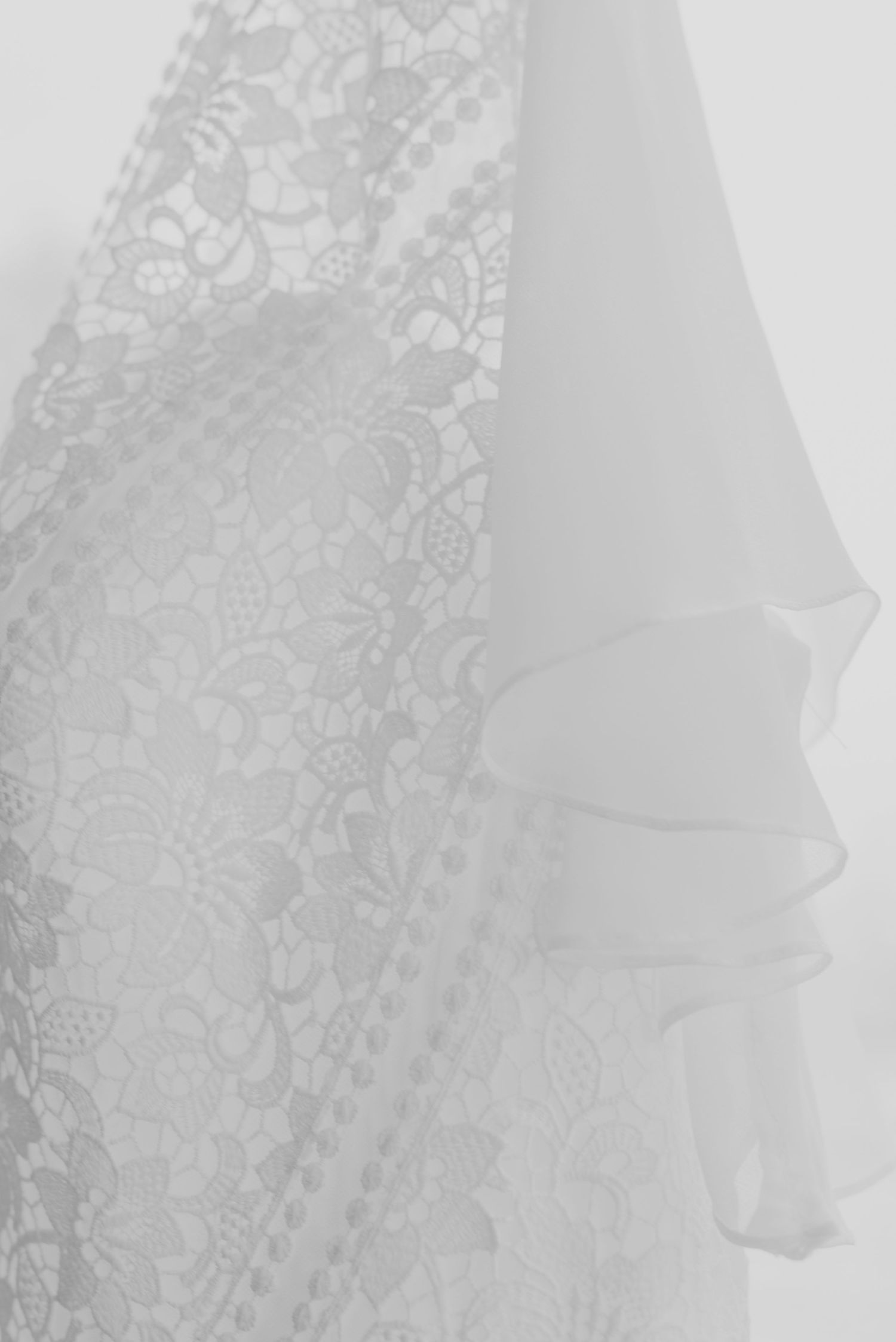 Close-up detail of delicate white lace and tulle wedding dress fabric.