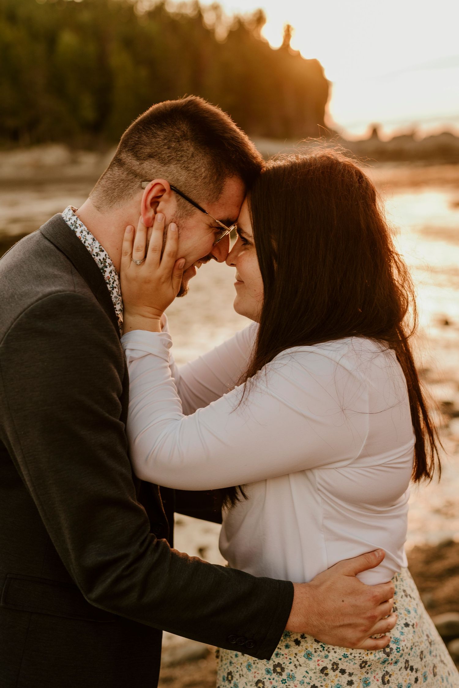 Intimate moment between couple during golden hour beach proposal.