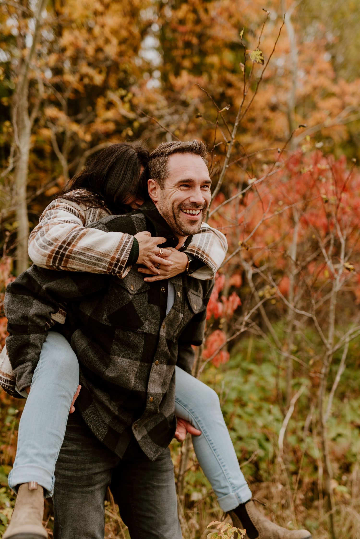 Joyful piggyback ride through vibrant autumn foliage.