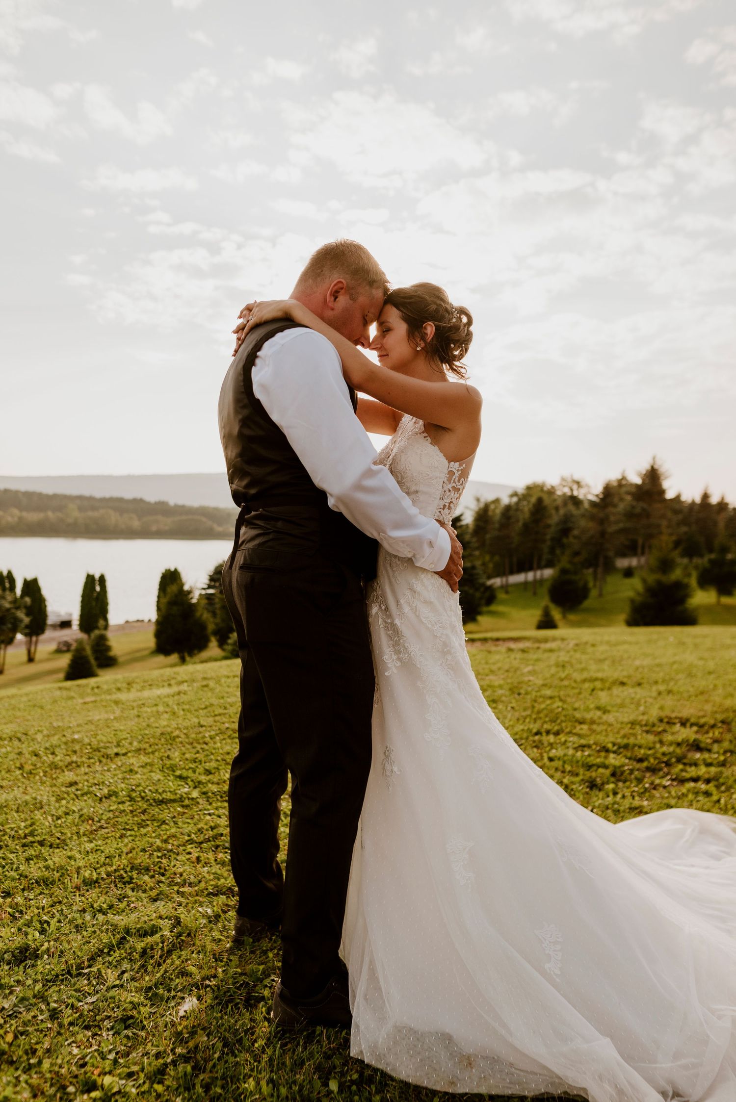 Golden hour wedding portrait on hillside with water view in background.