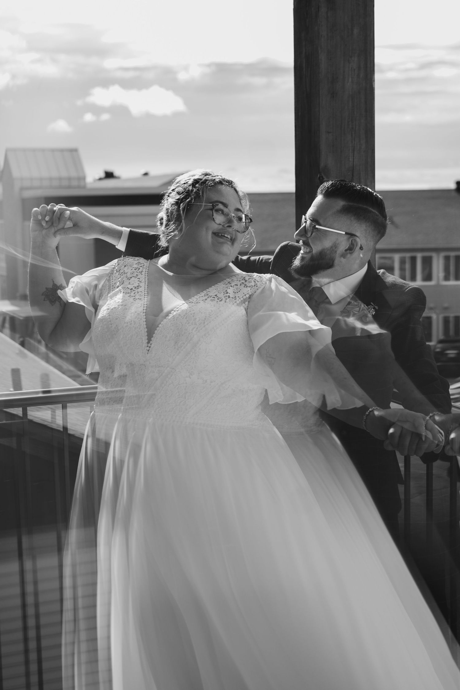 Couple dancing and laughing together on outdoor deck at wedding venue.