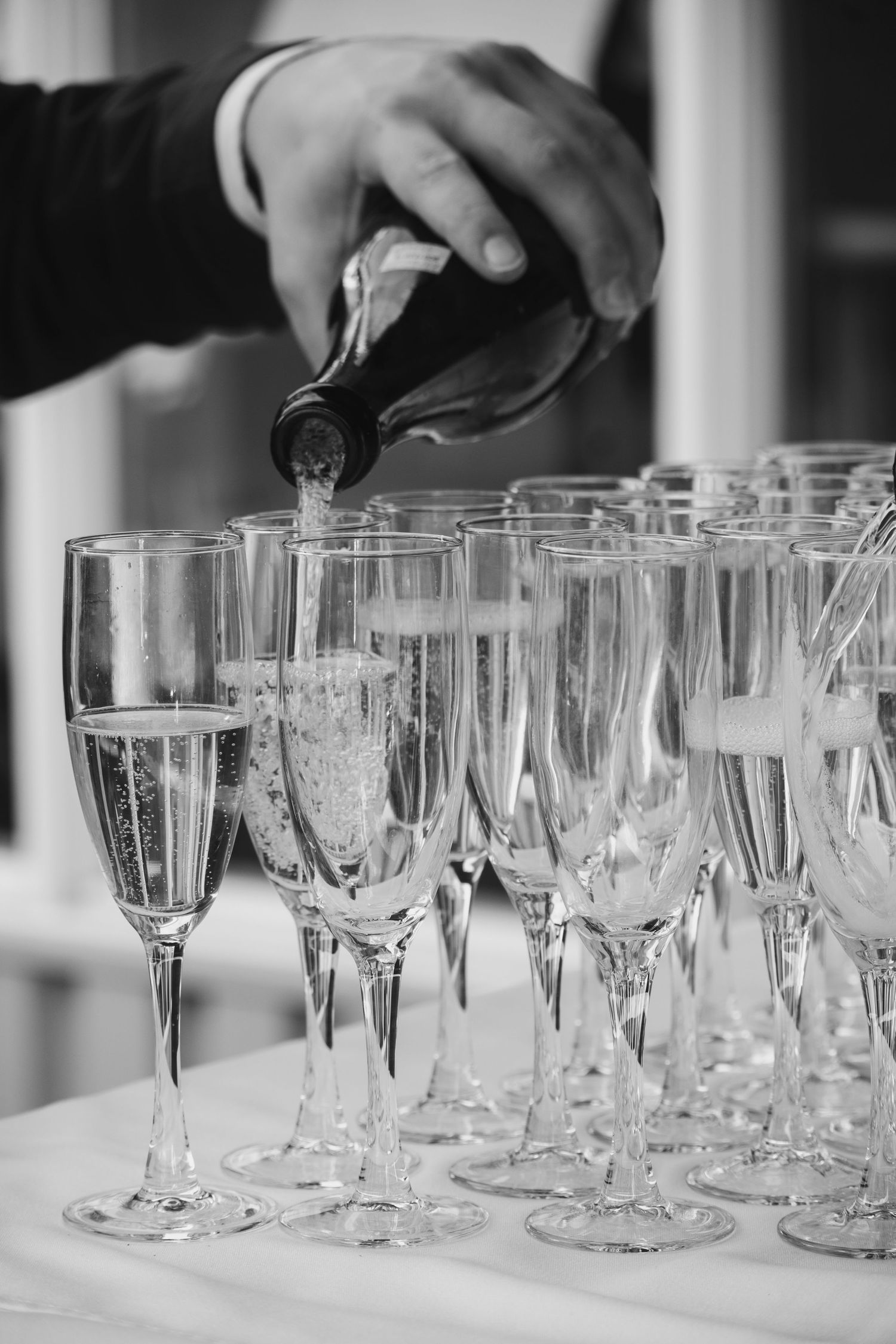 Champagne being poured into multiple flute glasses at wedding reception.