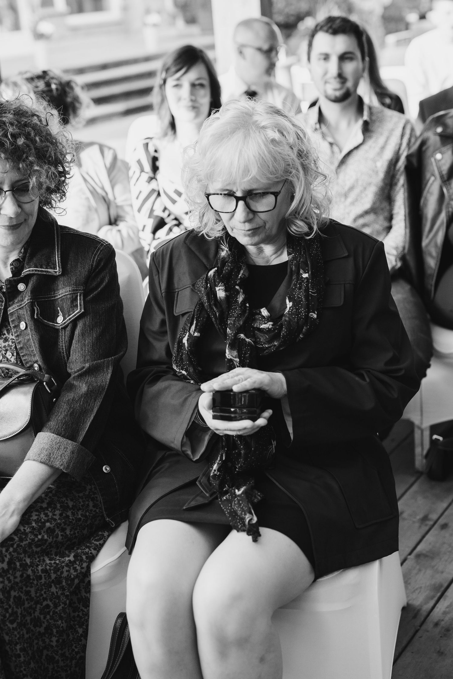 Guests using mobile phones during wedding event in black and white photography.